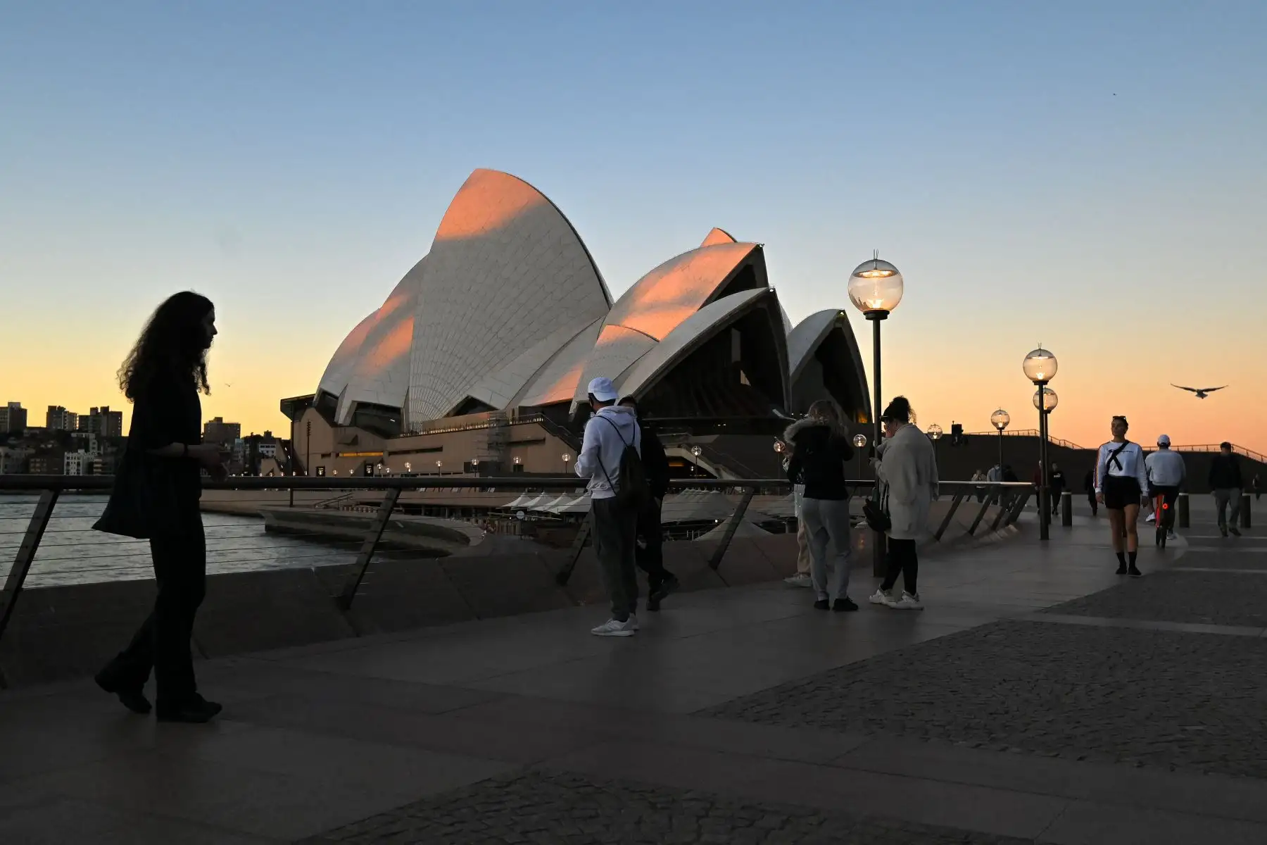 Un pequeño número de personas se para frente a la Ópera de Sydney en Circular Quay, generalmente lleno de visitantes el fin de semana, en el centro de Sydney, en el primer día completo de un bloqueo de coronavirus de dos semanas para contener un brote. 
Foto: AFP