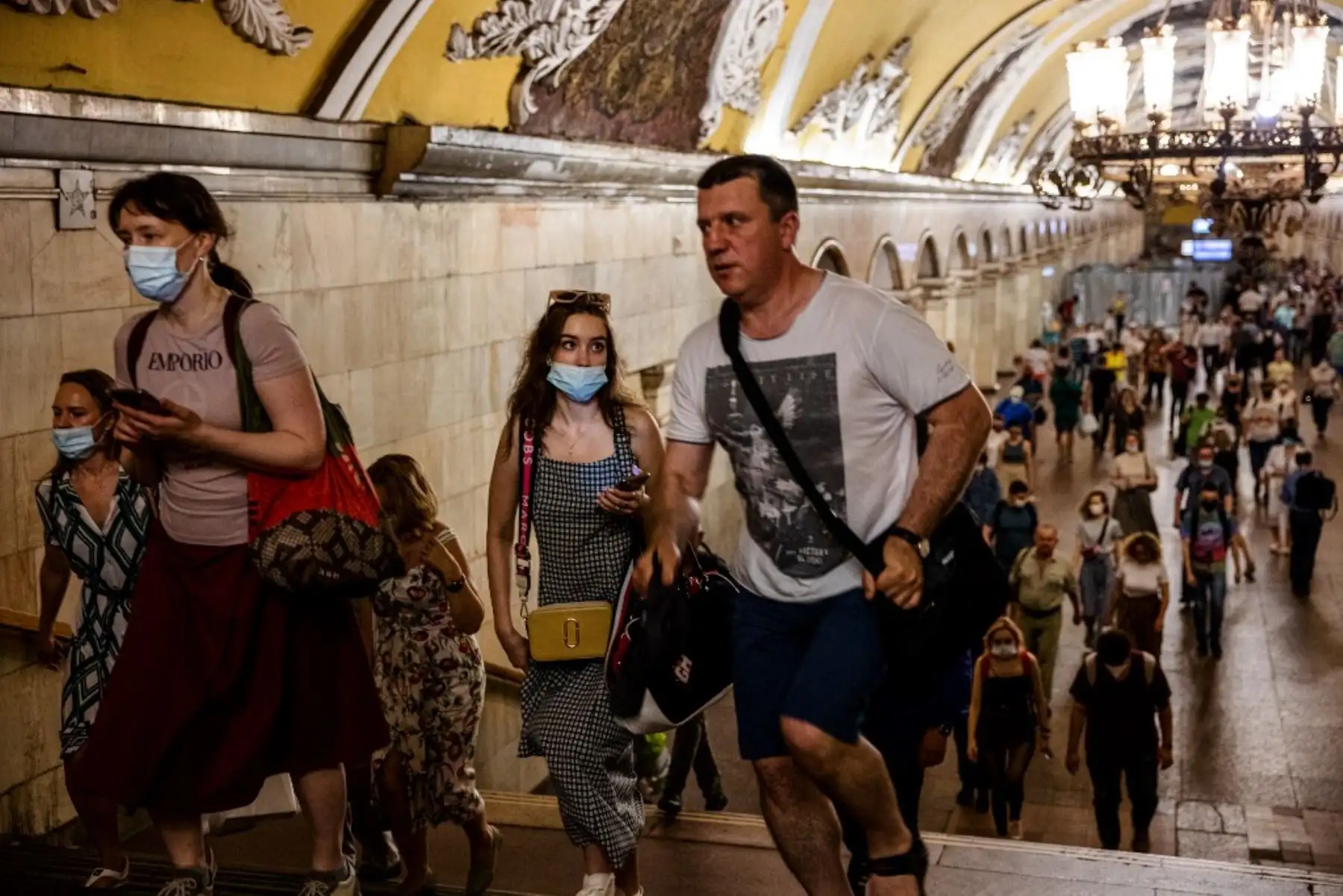 Viajeros, algunos con máscaras faciales, caminan sobre una plataforma en el metro de Moscú. Foto: AFP