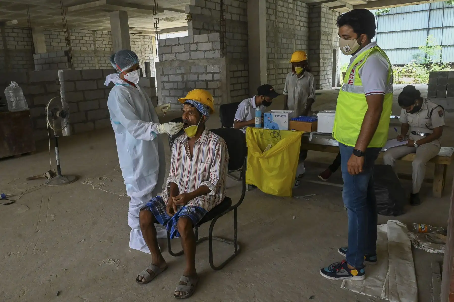 Un trabajador de la salud toma una muestra de un hisopo de un obrero para una prueba de PCR para el coronavirus, en un sitio de construcción en Nueva Delhi, el 10 de junio de 2021. Foto: AFP