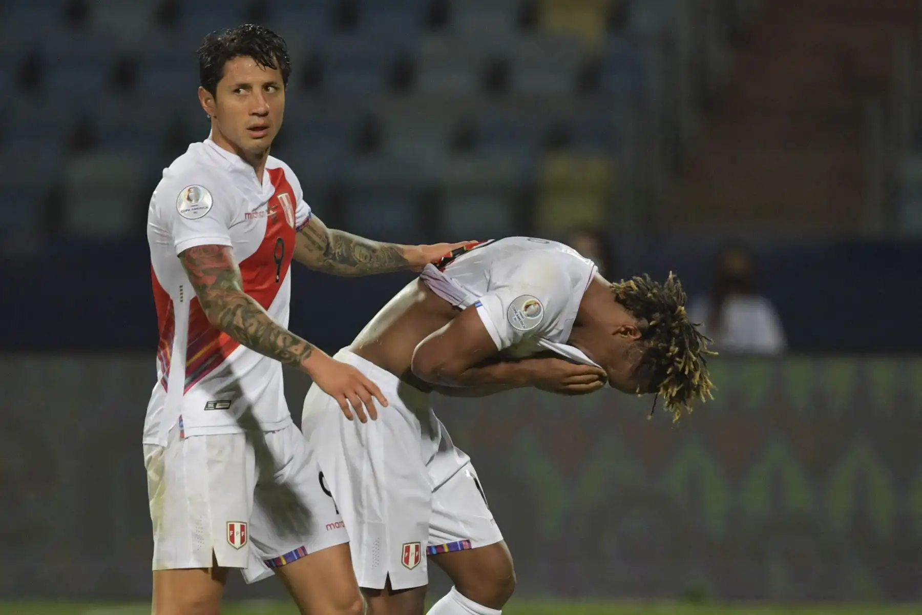 El peruano Gianluca Lapadula consuela a su compañero Andre Carrillo luego que le mostraran tarjeta roja durante el partido de cuartos de final del torneo de fútbol Conmebol 2021, en el Estadio Olímpico de Goiania, Brasil. Foto: AFP