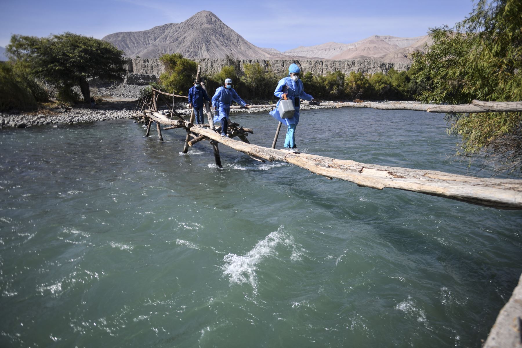 Trabajadores de salud cruzan el río Camaná para inocular a ancianos con dosis de la vacuna Pfizer-BioNTech contra COVID-19, en Arequipa, sur de Perú