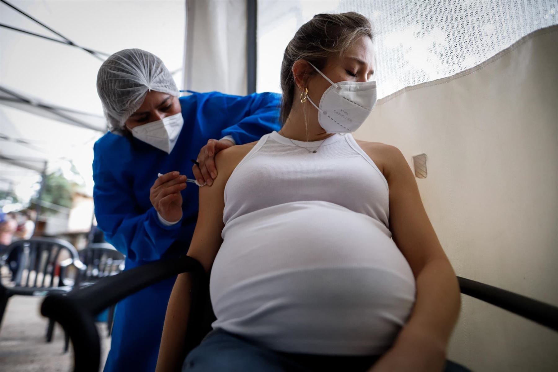 Personal médico aplica una dosis de vacuna contra el covid-19 a una mujer embarazada.