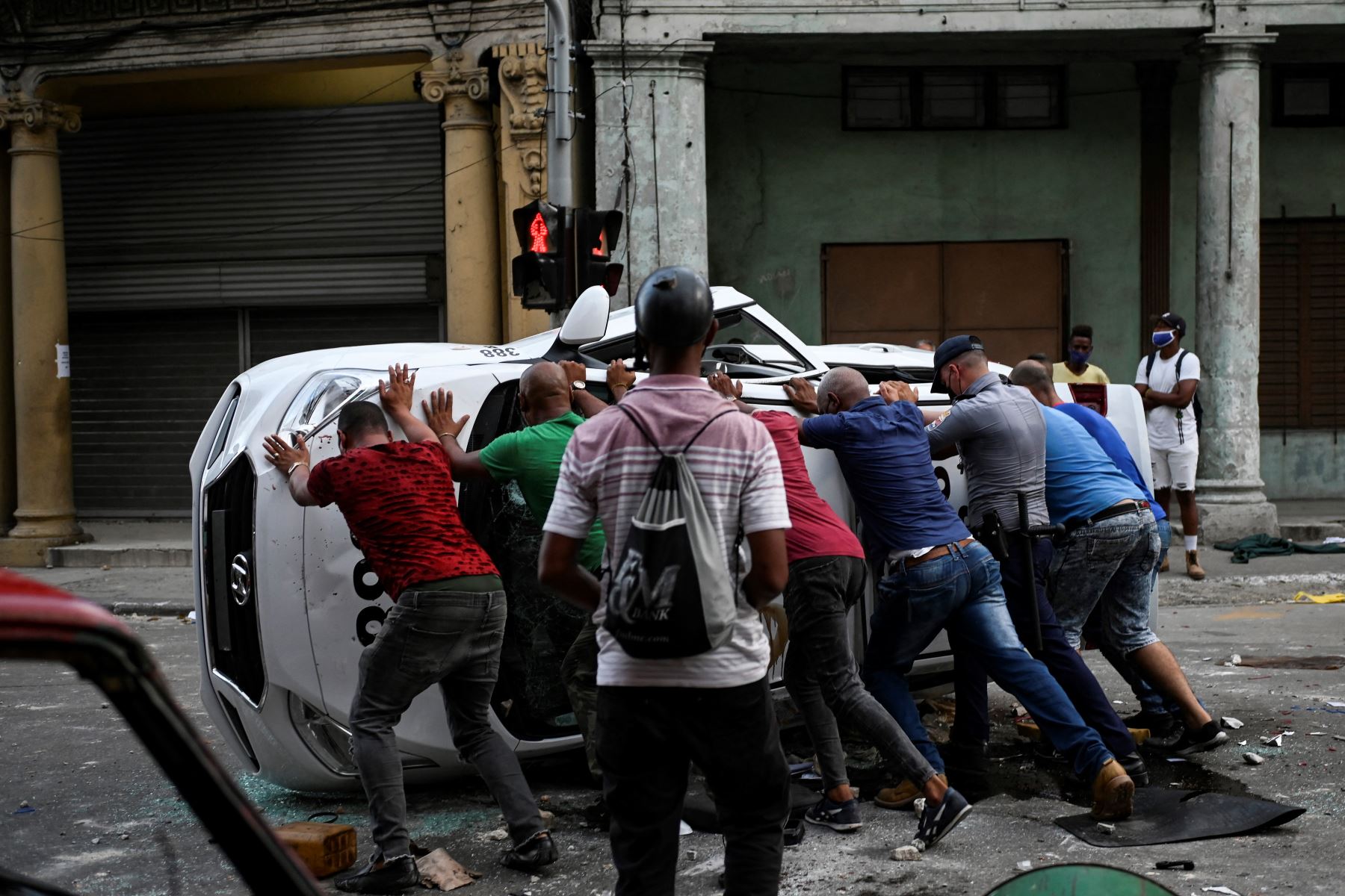 La gente empuja un automóvil volcado en la calle en el marco de una manifestación contra el presidente cubano Miguel Díaz-Canel en La Habana. Foto: AFP