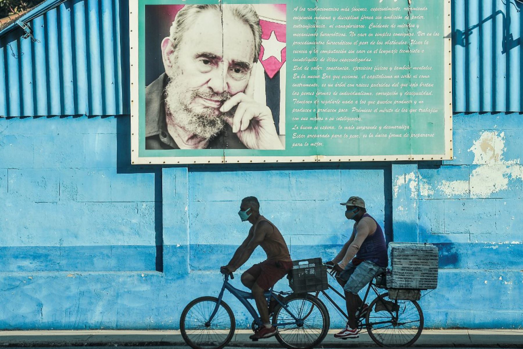 Hombres viajan en sus bicicletas cerca de un cartel del fallecido líder cubano Fidel Castro en La Habana. Foto. AFP