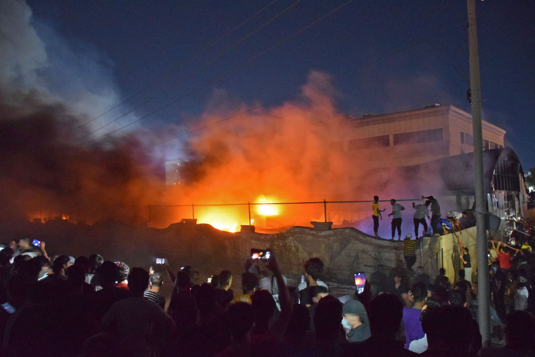 La gente toma imágenes de las llamas cuando un incendio masivo envuelve la sala de aislamiento del coronavirus del hospital Al-Hussein en la ciudad de Nasiriyah, en el sur de Irak.
Foto: AFP