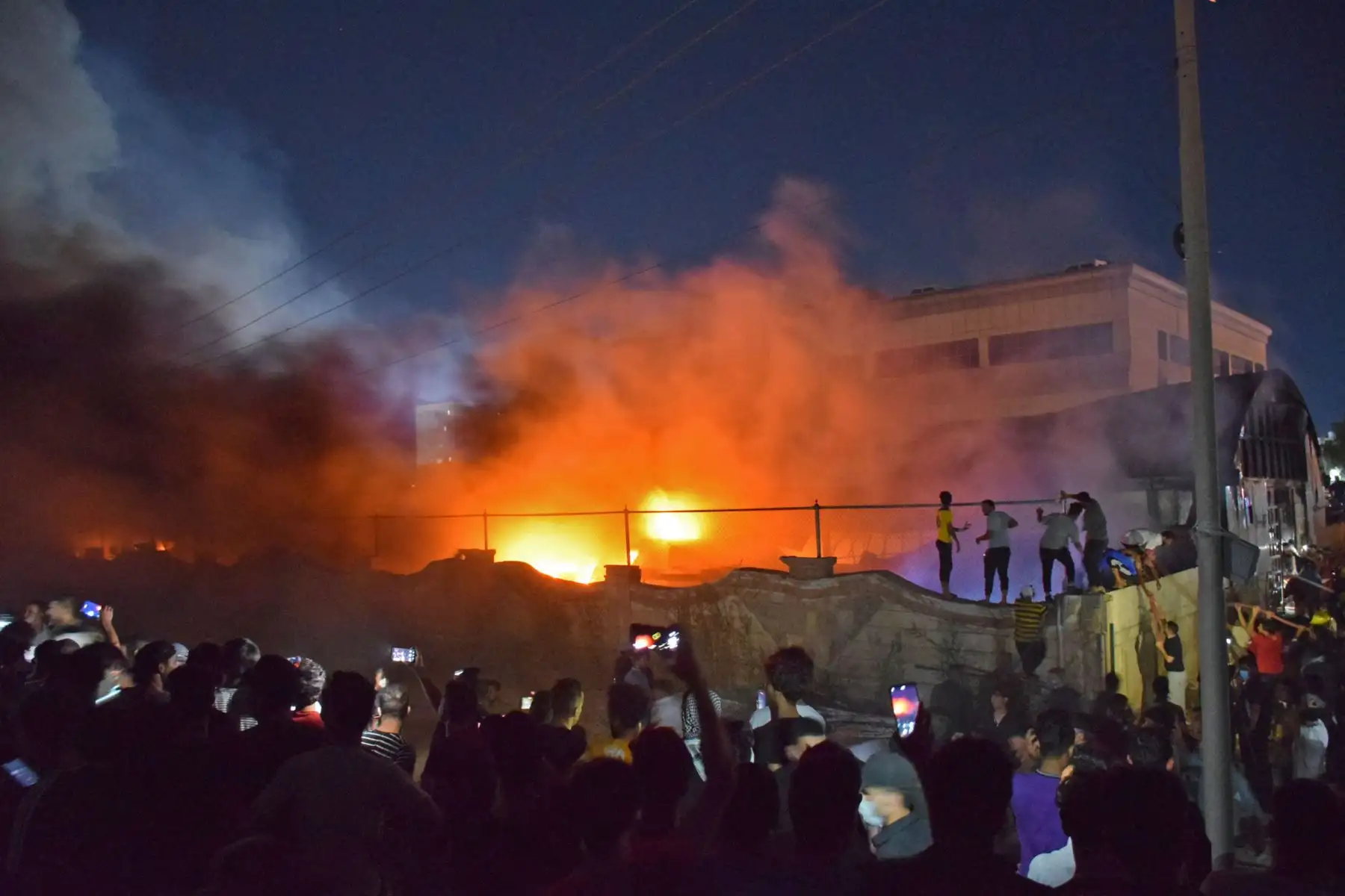 La gente toma imágenes de las llamas cuando un incendio masivo envuelve la sala de aislamiento del coronavirus del hospital Al-Hussein en la ciudad de Nasiriyah, en el sur de Irak.
Foto: AFP