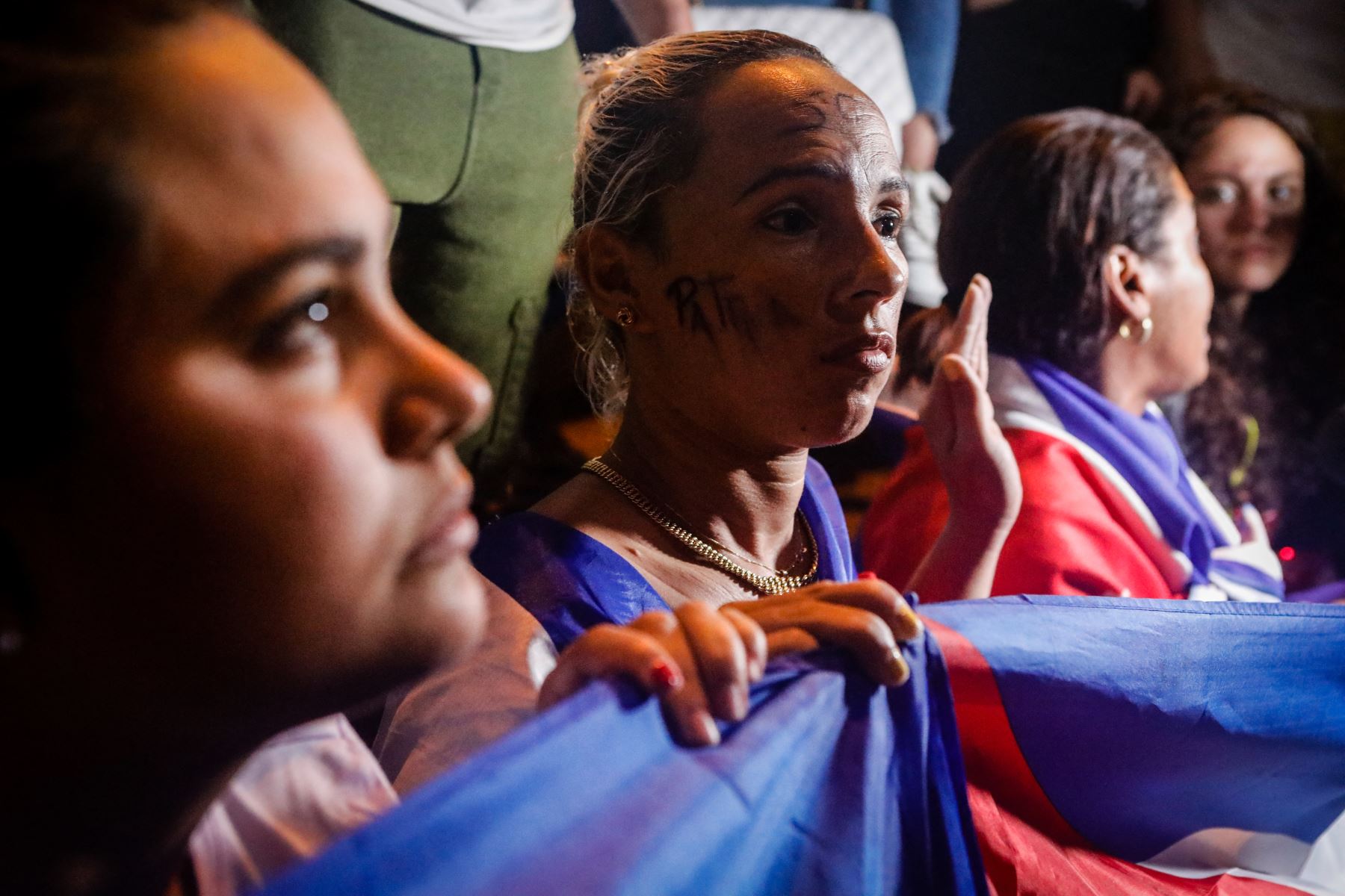 Las mujeres se arrodillan y sostienen una bandera cubana mientras bloquean la autopista Palmetto Expressway durante una protesta de apoyo a los cubanos que se manifiestan contra su gobierno, en Miami. Foto: AFP