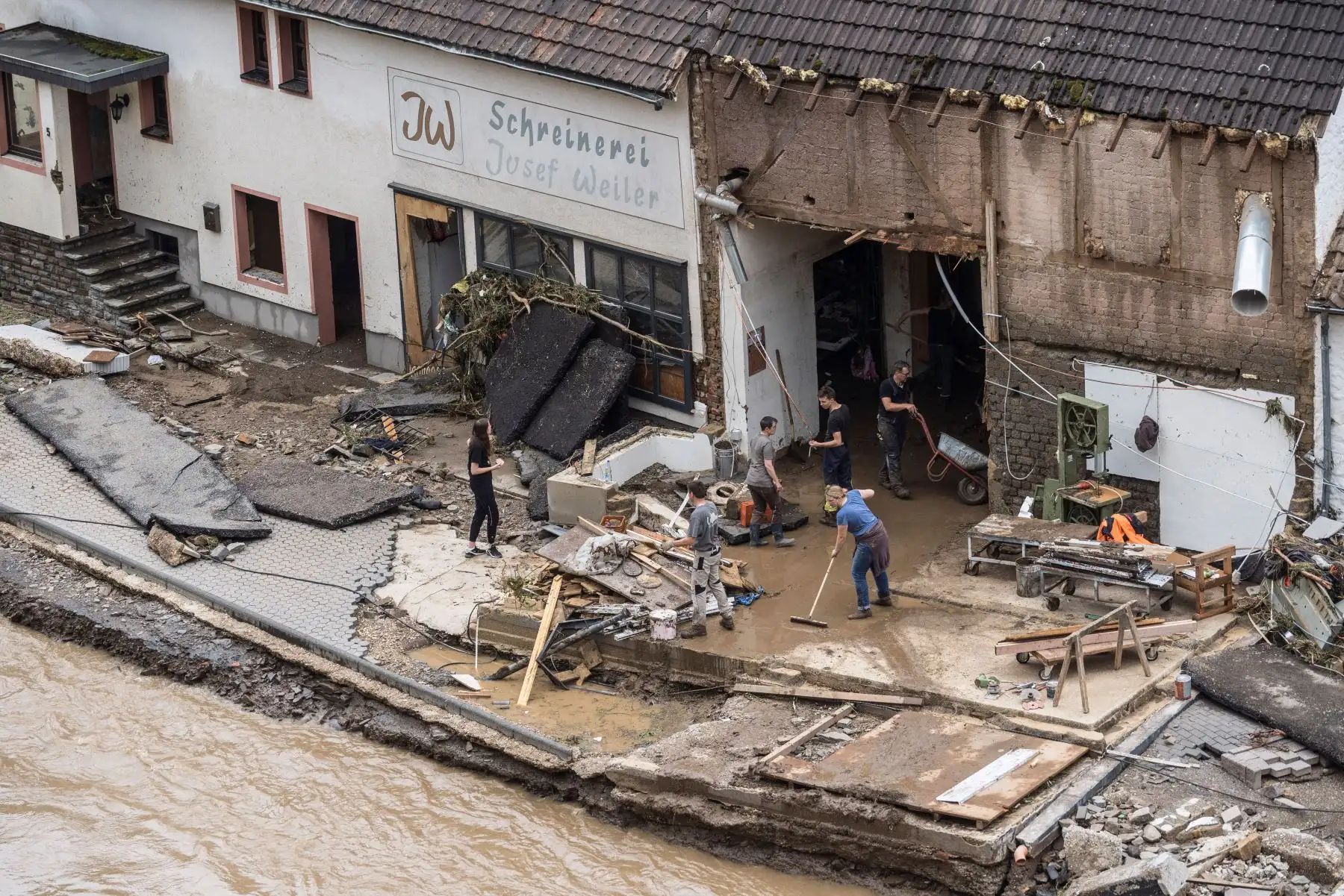 Las personas intentan eliminar las inundaciones de una casa destruida en Schuld, cerca de Bad Neuenahr, en el oeste de Alemania. Las intensas lluvias e inundaciones que azotan Europa occidental han matado al menos a 42 personas en Alemania y han dejado muchas más desaparecidas, ya que las aguas crecieron. Foto: AFP