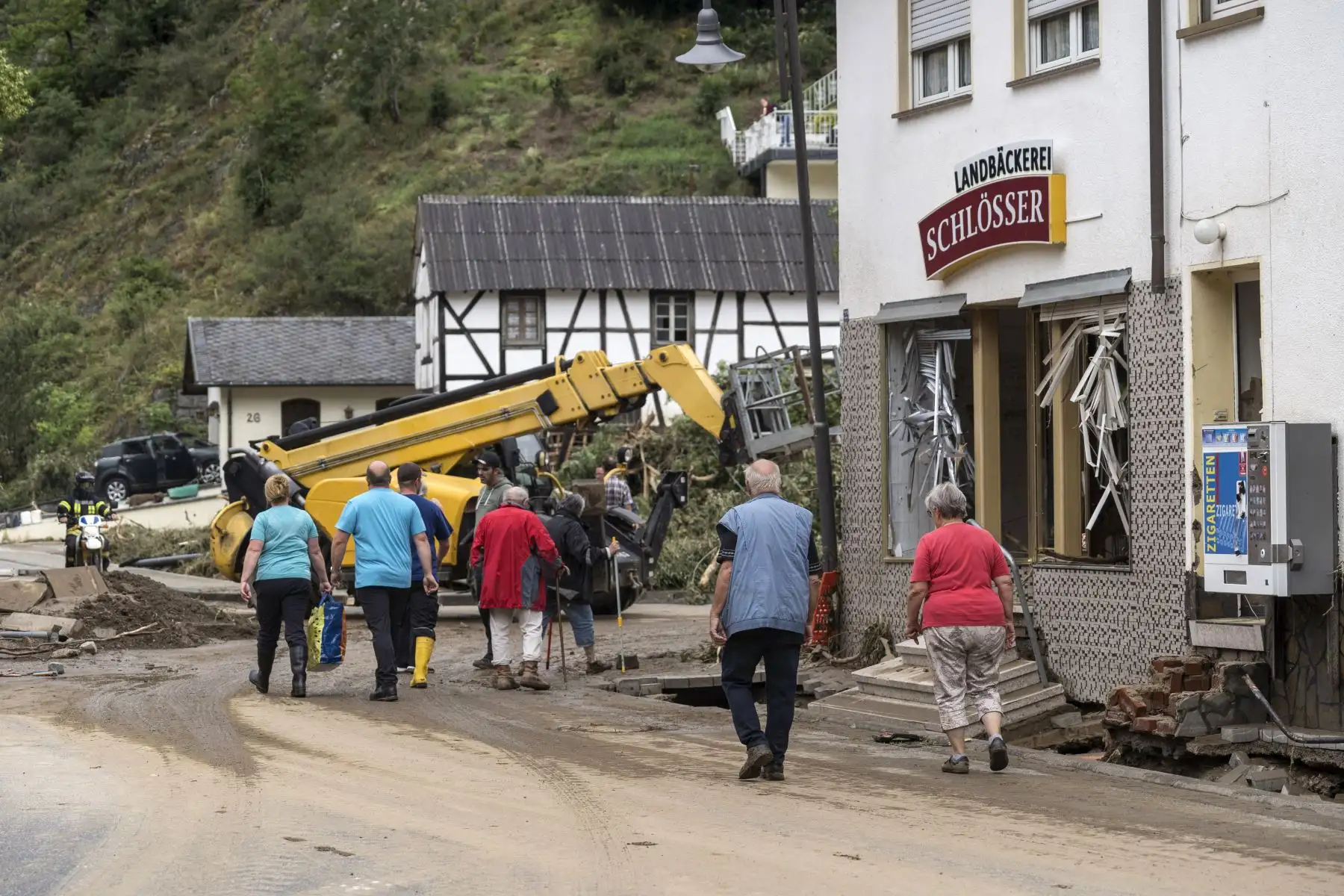 La gente pasa junto a las ventanas dañadas de una panadería mientras las calles se despejan después de las fuertes lluvias e inundaciones en el municipio de Schuld, cerca de Bad Neuenahr, en el oeste de Alemania, el 15 de julio de 2021. Foto: AFP