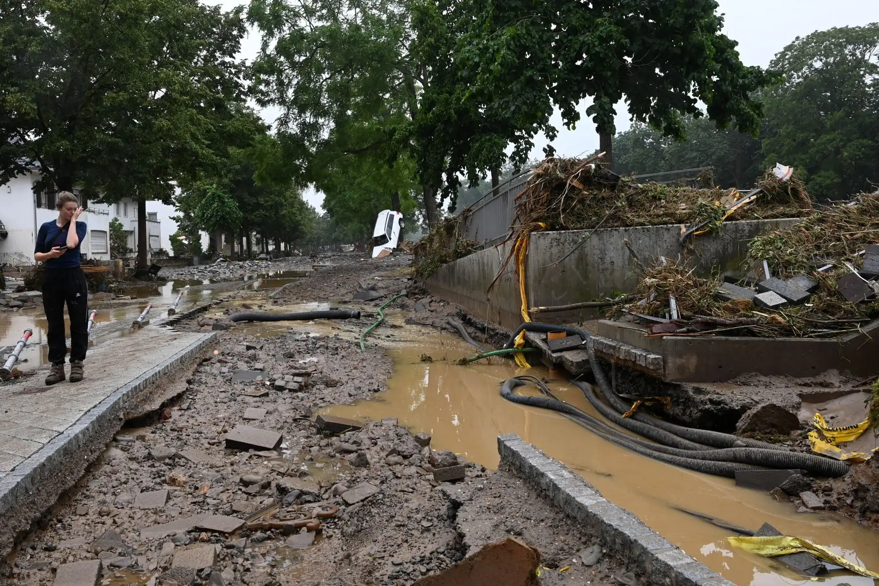 Una mujer mira los escombros en una carretera en medio y al lado de un automóvil parado contra un árbol después de que las inundaciones causaron daños importantes en Bad Neuenahr-Ahrweiler, en el oeste de Alemania. Foto: AFP