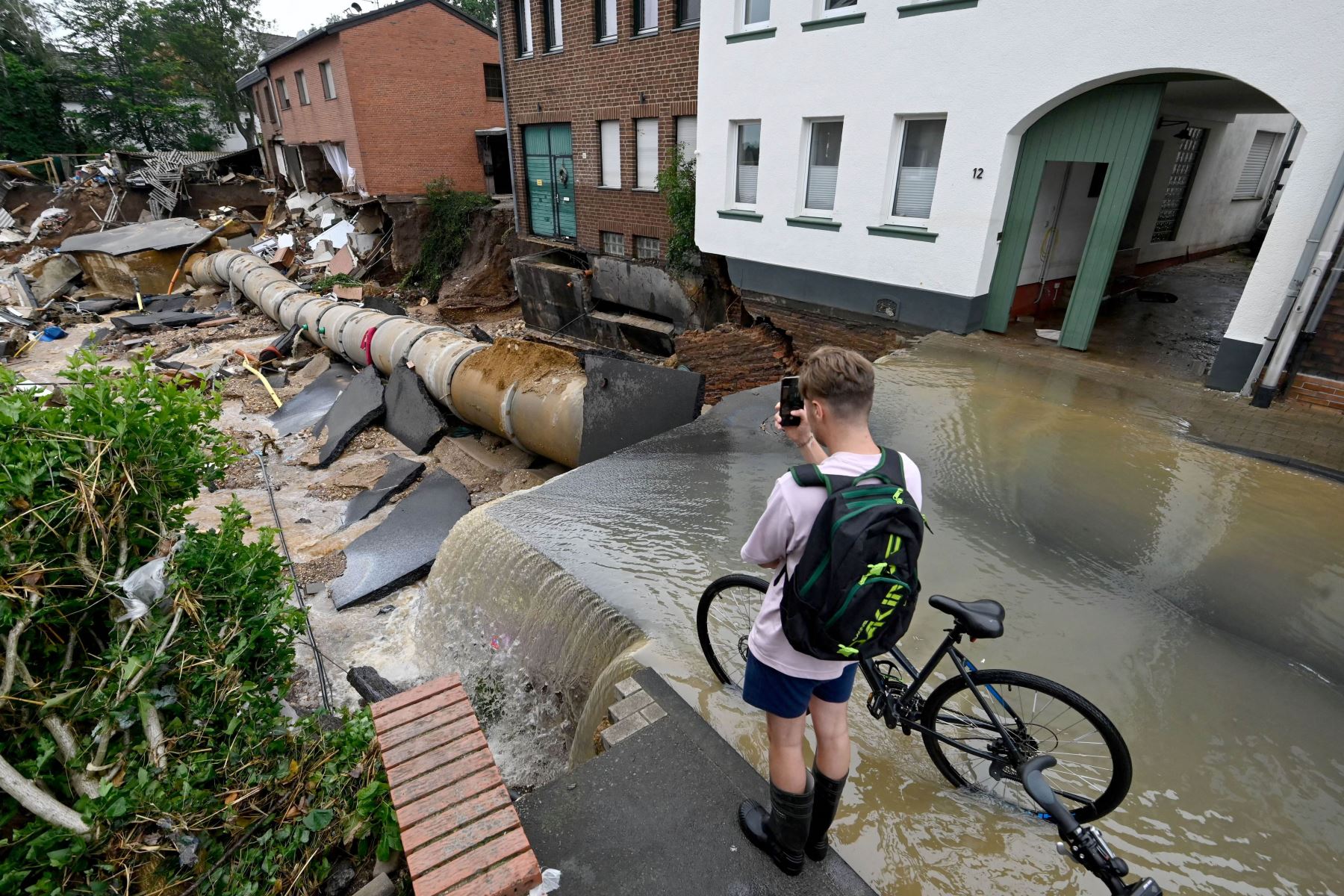 Un ciclista toma fotografías de un área completamente destruida por las inundaciones en el distrito Blessem de Erftstadt, en el oeste de Alemania. Foto: AFP