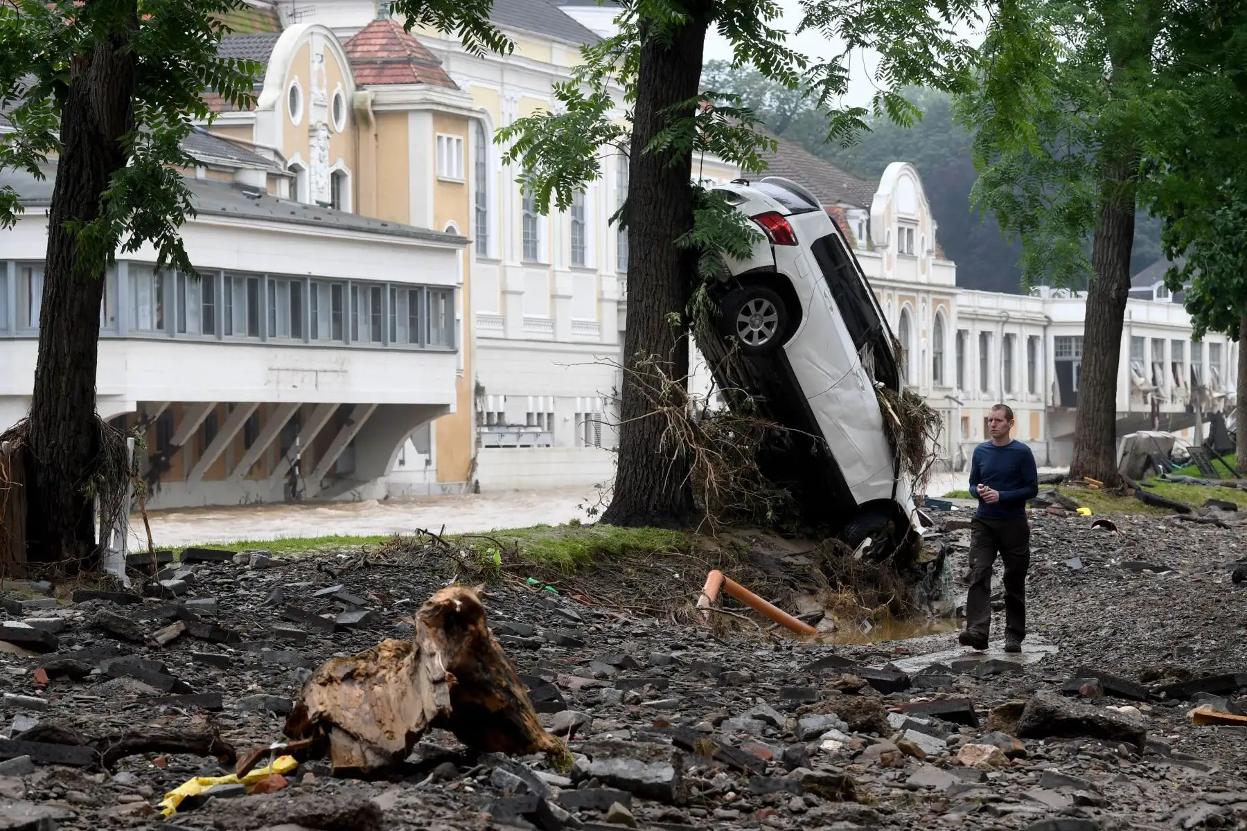 Un hombre pasa junto a un automóvil destruido presionado contra un árbol por los torrentes después de que las inundaciones causaron daños importantes en Bad Neuenahr-Ahrweiler, en el oeste de Alemania. Foto: AFP