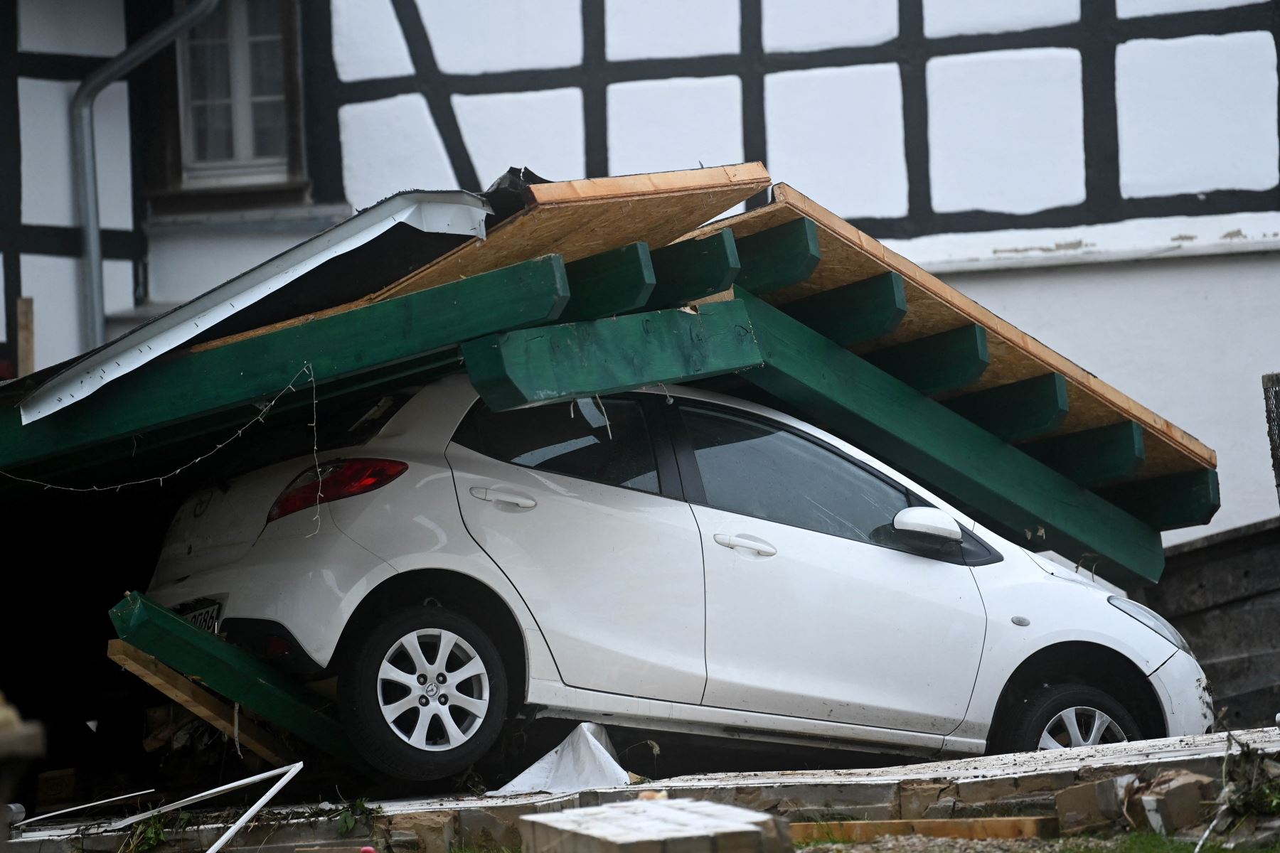 Un automóvil está cubierto de escombros en Iversheim, cerca de Bad Muenstereifel, en el oeste de Alemania, el 16 de julio de 2021, luego de fuertes lluvias e inundaciones. - El número de muertos por inundaciones devastadoras en Europa se disparó a al menos 126 el 16 de julio. Foto: AFP