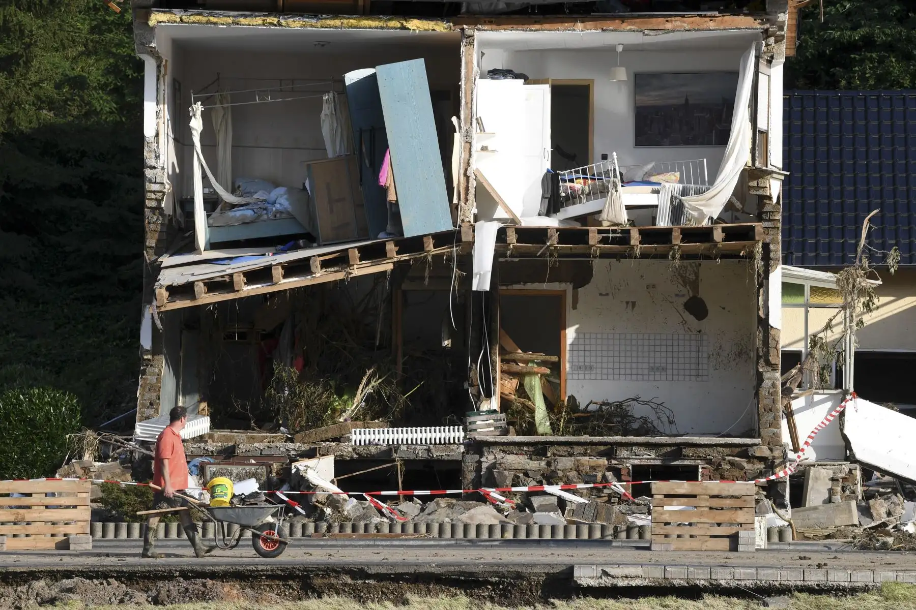 Un hombre empuja una carretilla frente a una casa destruida en la pequeña ciudad de Dernau, Renania-Palatinado, Alemania occidental. Foto: AFP