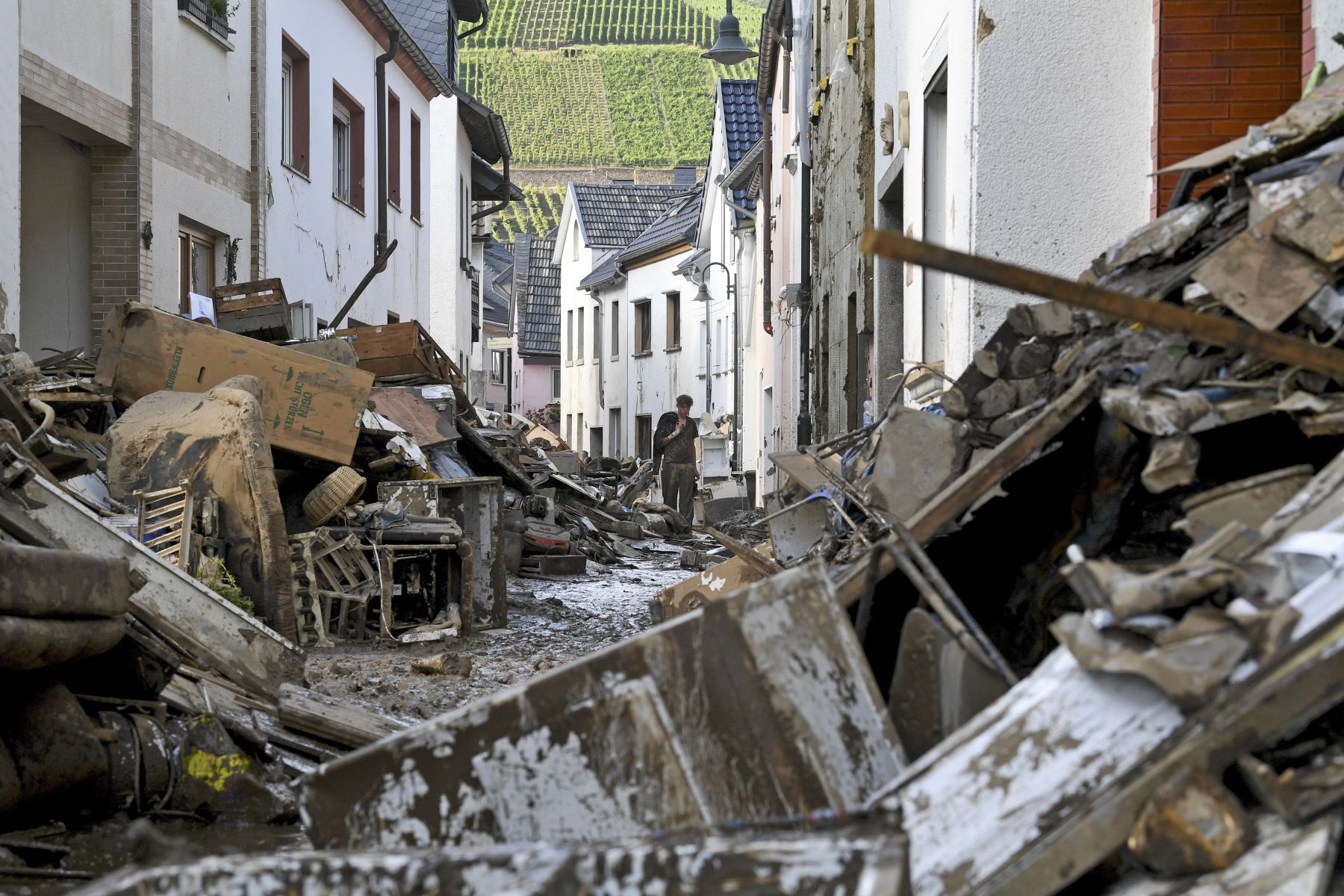 Un residente camina por una calle llena de escombros, muebles y enseres domésticos destruidos, en la ciudad de Dernau, en el oeste de Alemania. Foto: AFP
