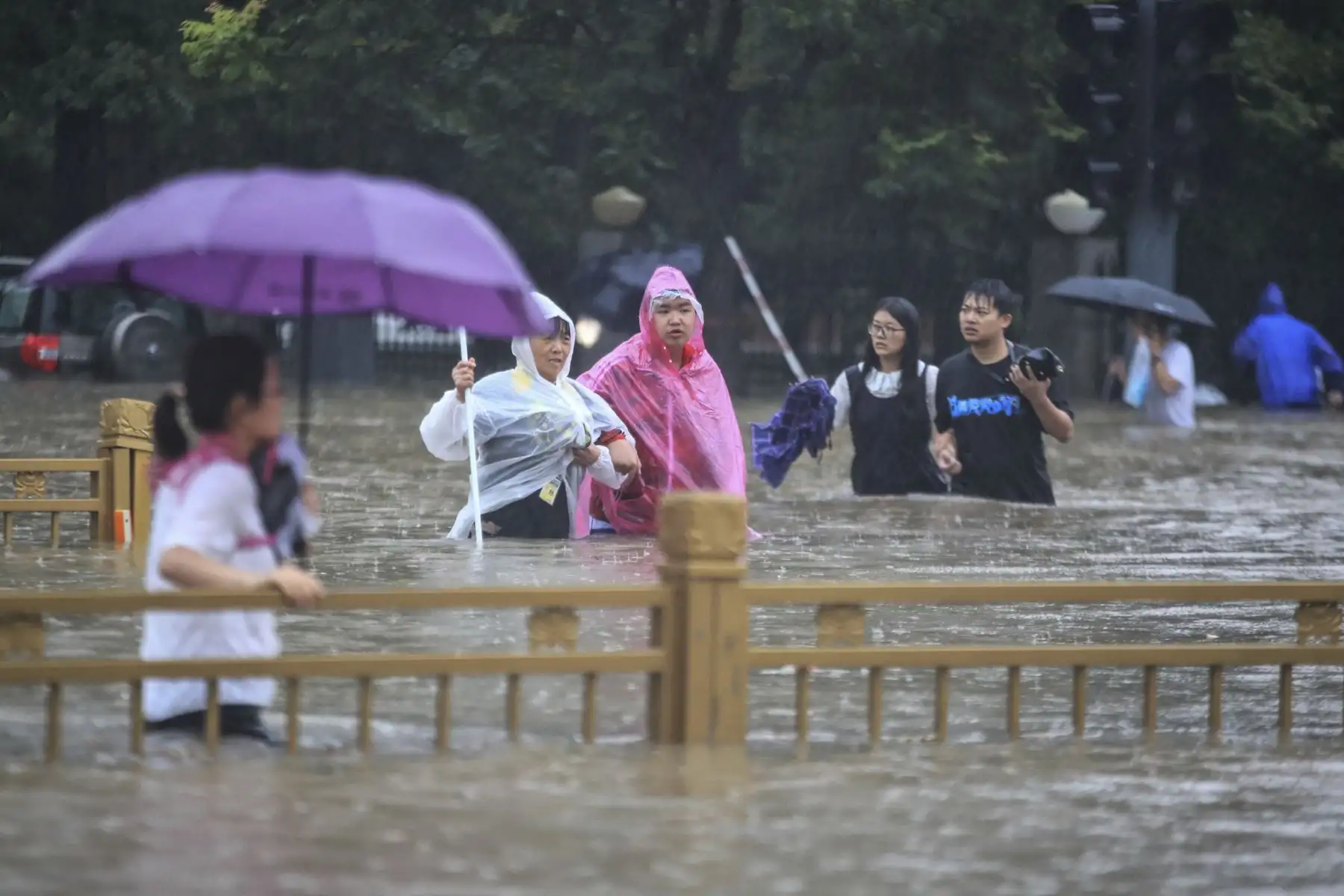 Un grupo de personas trata de cruzar una vía completamente inundada en Zhengzhou por las fuertes lluvias, en la provincia de Henan, en China. Foto: AFP