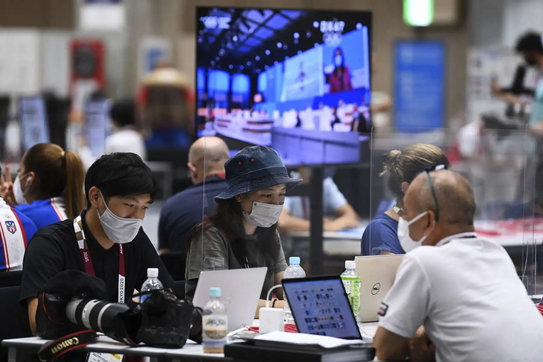 Periodistas con mascarillas como medida preventiva contra el coronavirus trabajan detrás del plexiglás protector, en el Centro de Prensa Principal, en Tokio. Foto: AFP