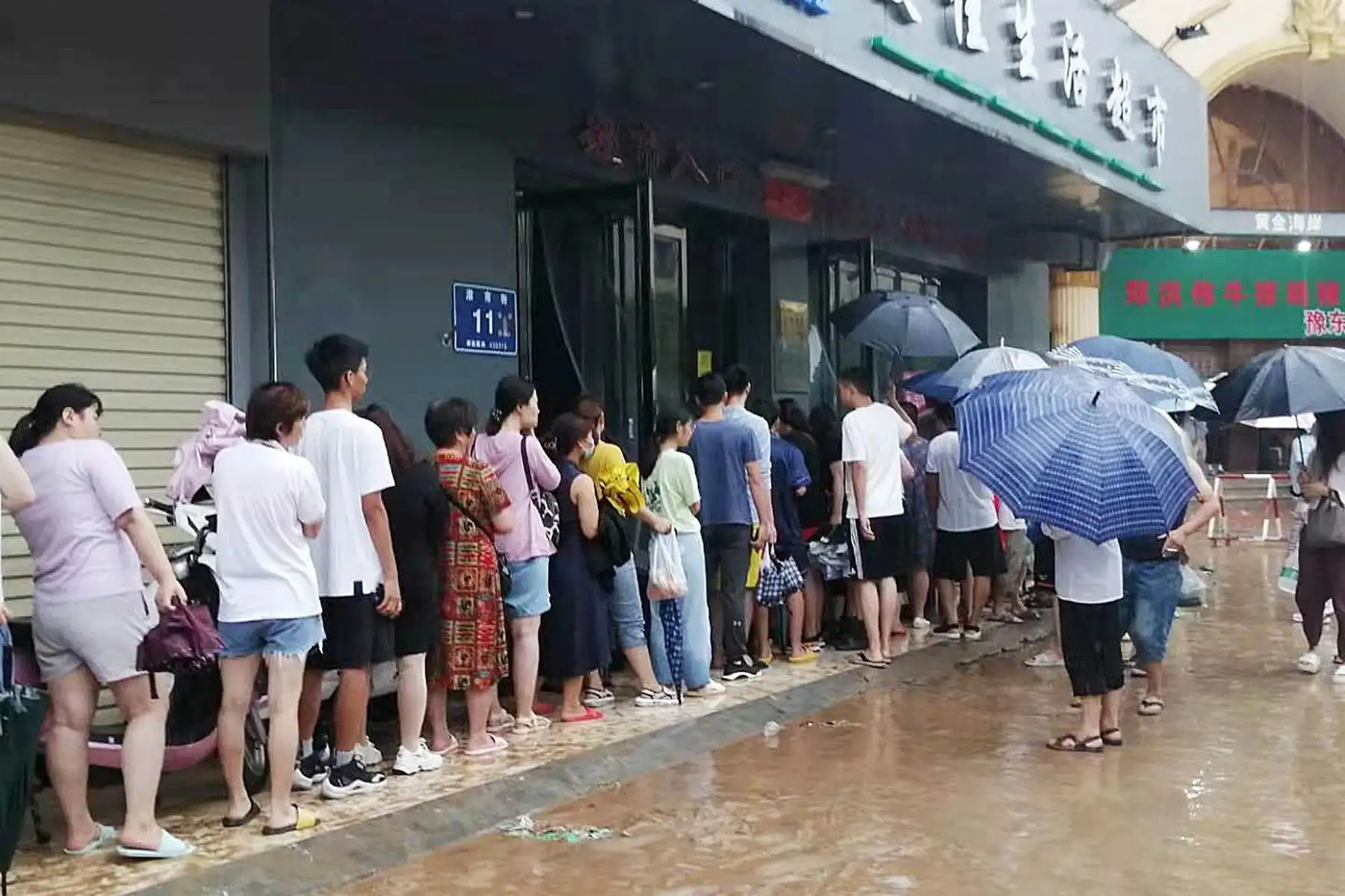 Personas hacen cola al lado de una pista inundada en medio de fuertes lluvias en Zhengzhou, provincia de Henan, China. Foto: EFE