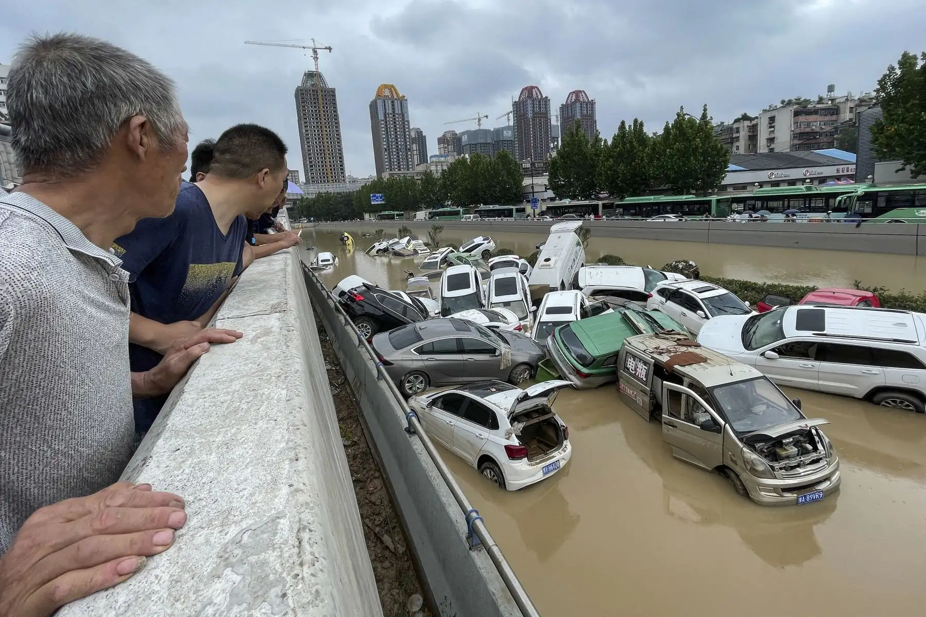Personas observan los automóviles que quedaron sumergidos tras las fuertes lluvias en la ciudad de Zhengzhou, en la provincia central de Henan, en China. Foto: AFP