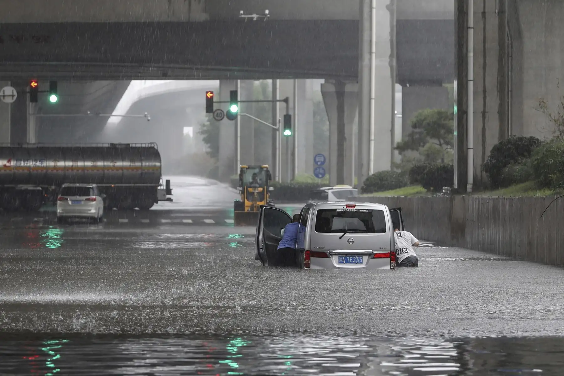 Personas tratan de empujar una camioneta atrapada tras las inundaciones por las fuertes lluvias en Zhengzhou, en la provincia de Henan, en China. Foto: AFP