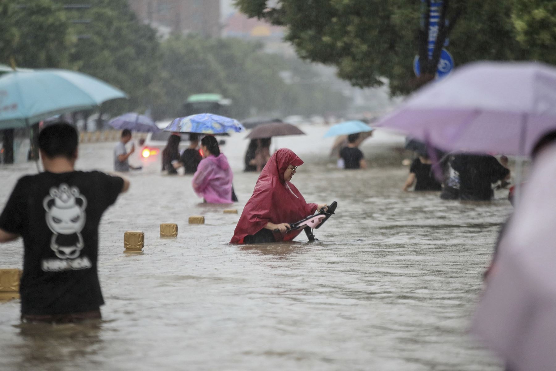 Un grupo de personas trata de cruzar una vía completamente inundada en Zhengzhou por las fuertes lluvias, en la provincia de Henan, en China. Foto: AFP