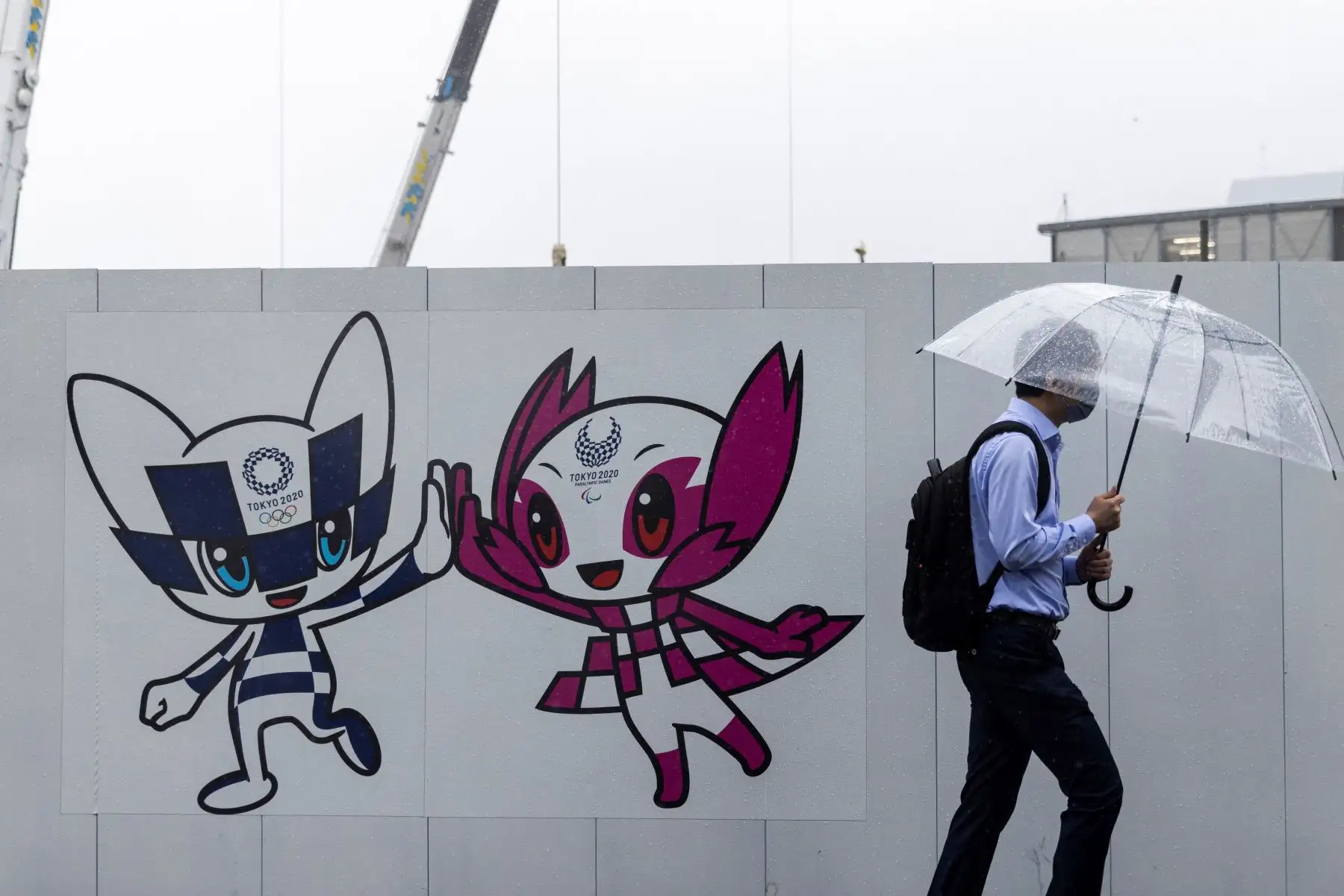 Un peatón pasa junto a un tablero de decoración de los Juegos Olímpicos y Paralímpicos de Tokio 2020 con ilustraciones de las mascotas de los Juegos Miraitowa (L) y Someity (R) en Tokio. Foto: AFP