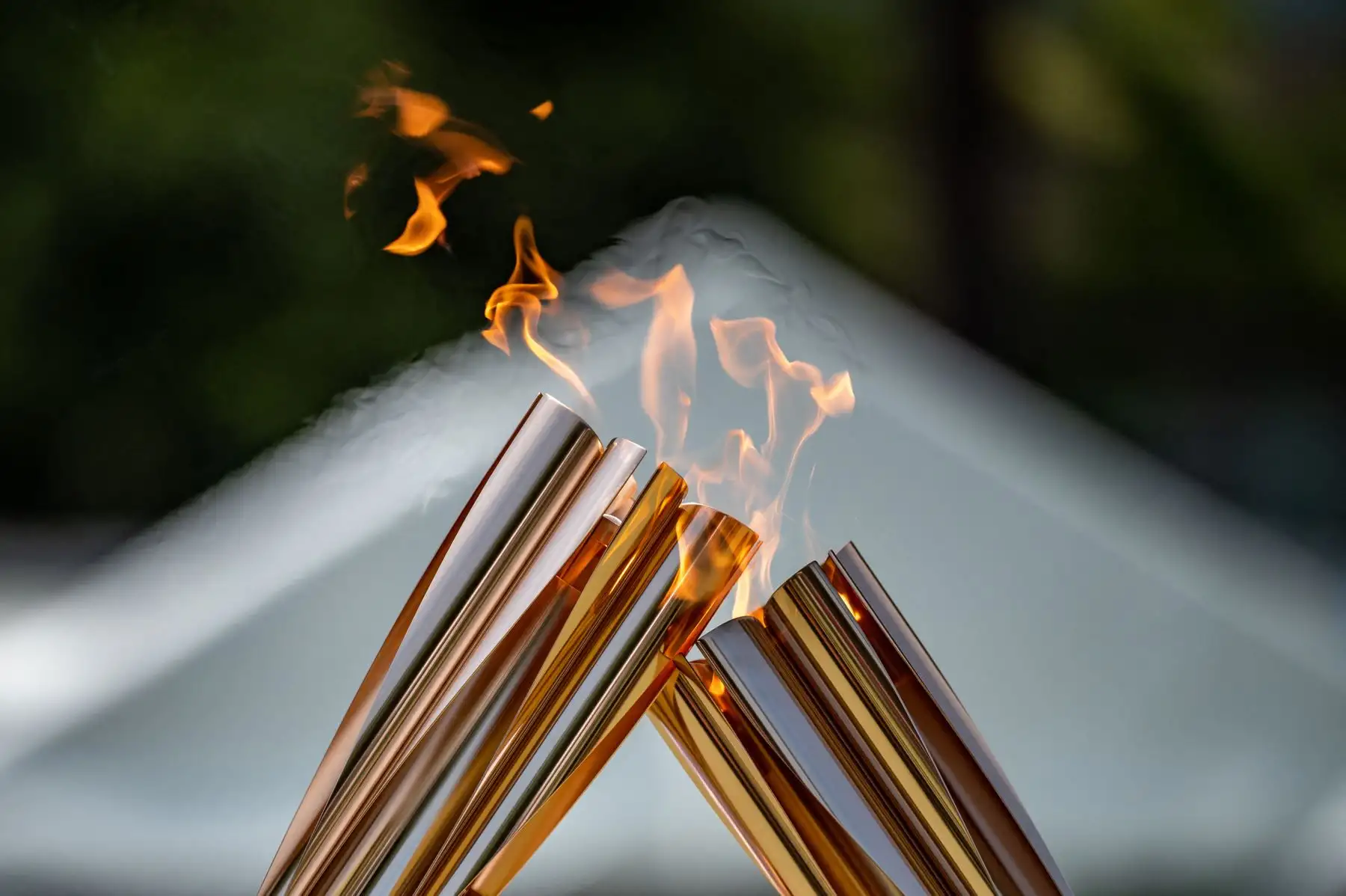 Los portadores de la antorcha transfieren la llama olímpica durante el beso de la antorcha en la ceremonia de encendido en el parque Hamacho en el distrito de Nihonbashi de Tokio. Foto: AFP