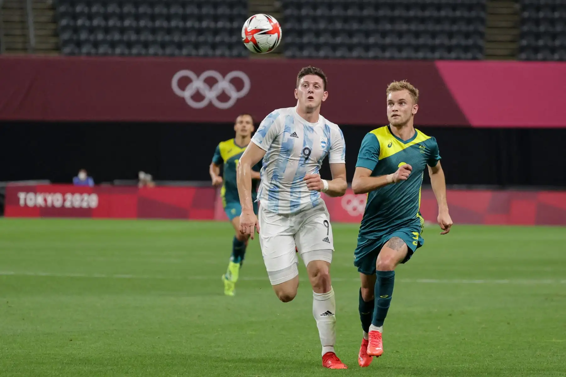 El delantero argentino Adolfo Gaich (C) compite por el balón con el defensor australiano Nathaniel Atkinson durante el partido de fútbol de primera ronda del grupo C masculino de los Juegos Olímpicos de Tokio 2020 entre Argentina y Australia en el Sapporo Dome. Foto: AFP