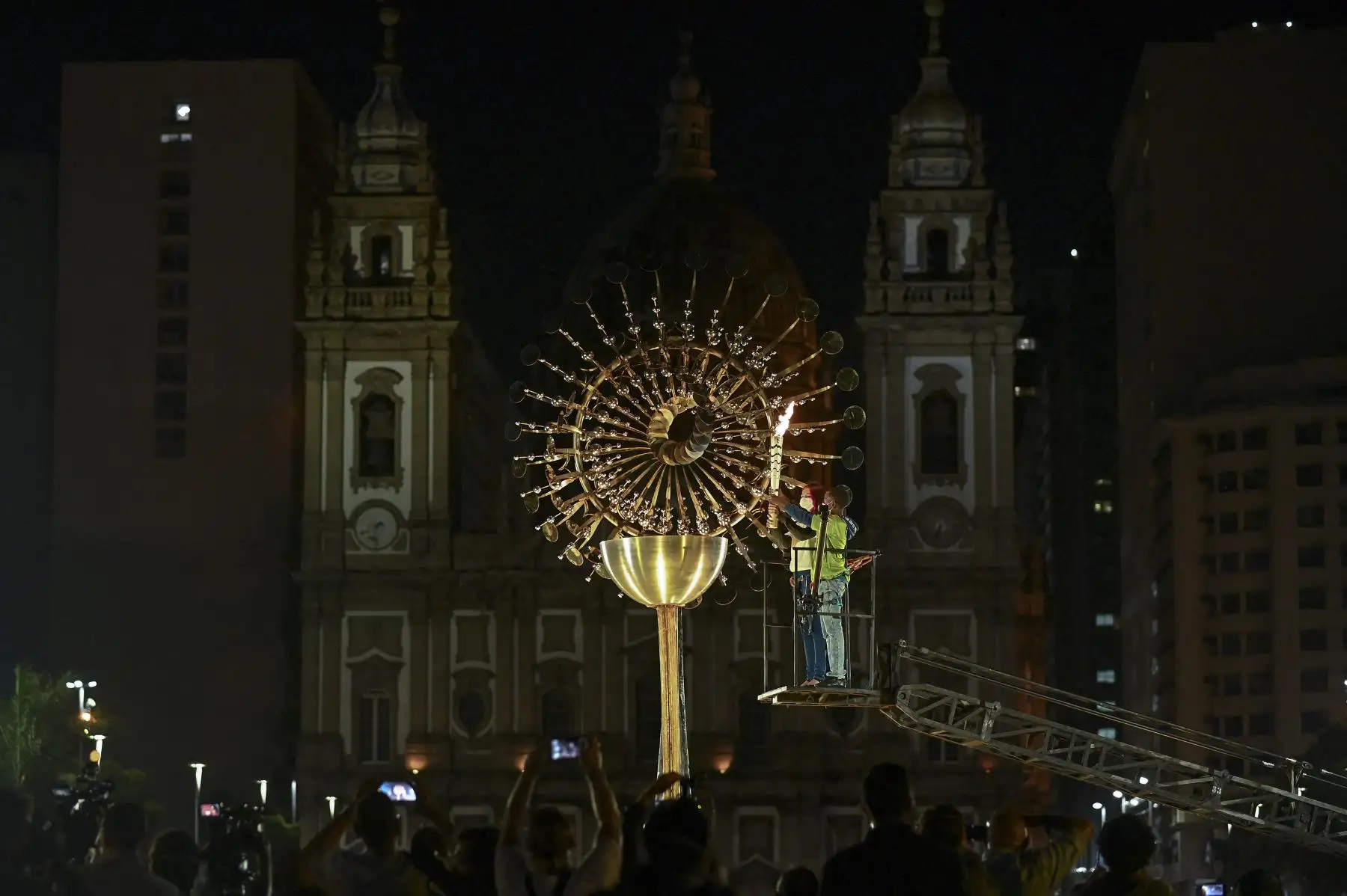 Niños quienes toman lecciones deportivas en una de las villas olímpicas municipales encendieron la réplica de la pira olímpica de Río 2016, frente a la iglesia de Candelaria en Río de Janeiro, Brasil. Foto: AFP