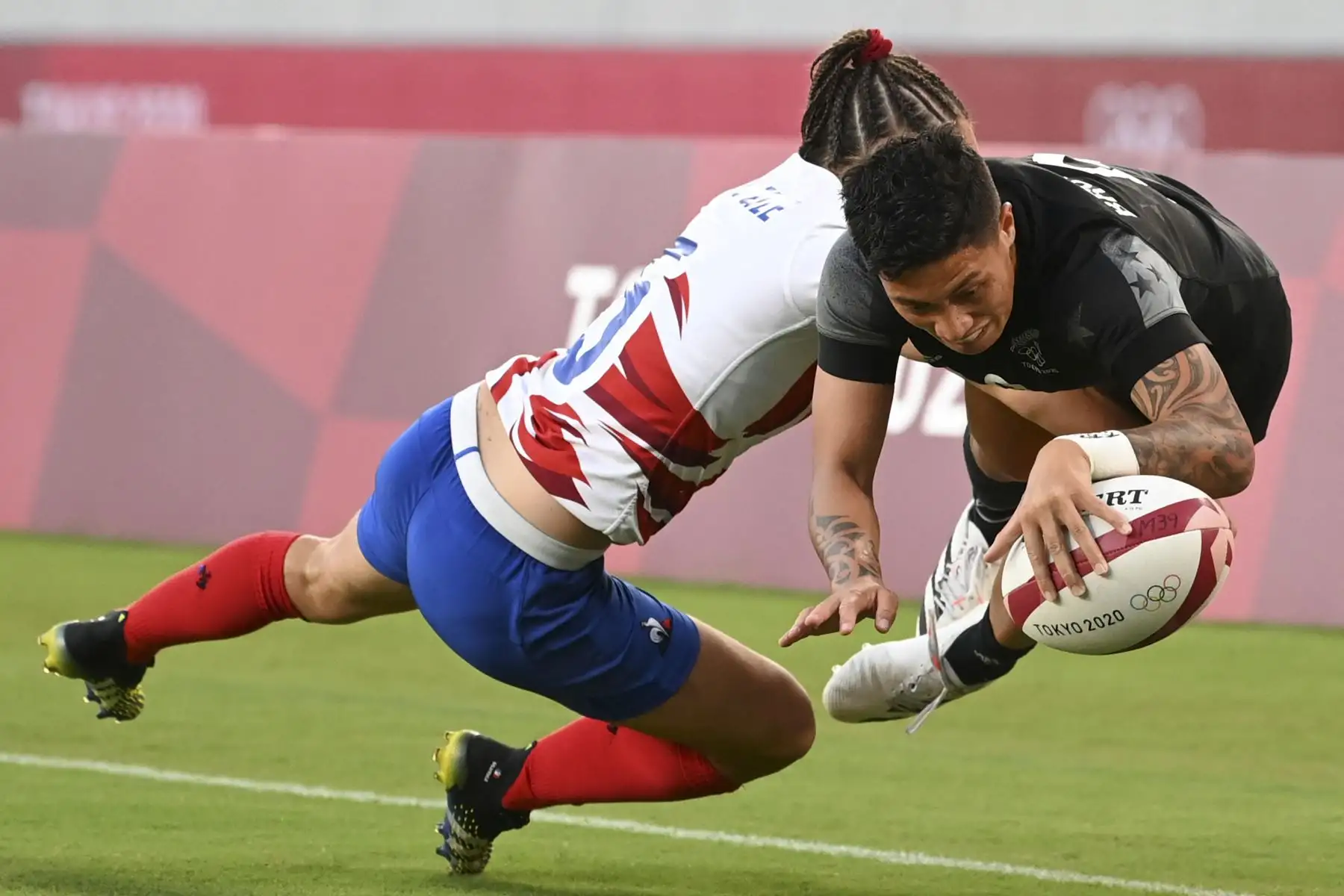 Gayle Broughton de Nueva Zelanda anota un try a pesar de una entrada de la francesa Jade Ulutule en el último partido femenino de rugby durante los Juegos Olímpicos de Tokio 2020. Foto: AFP