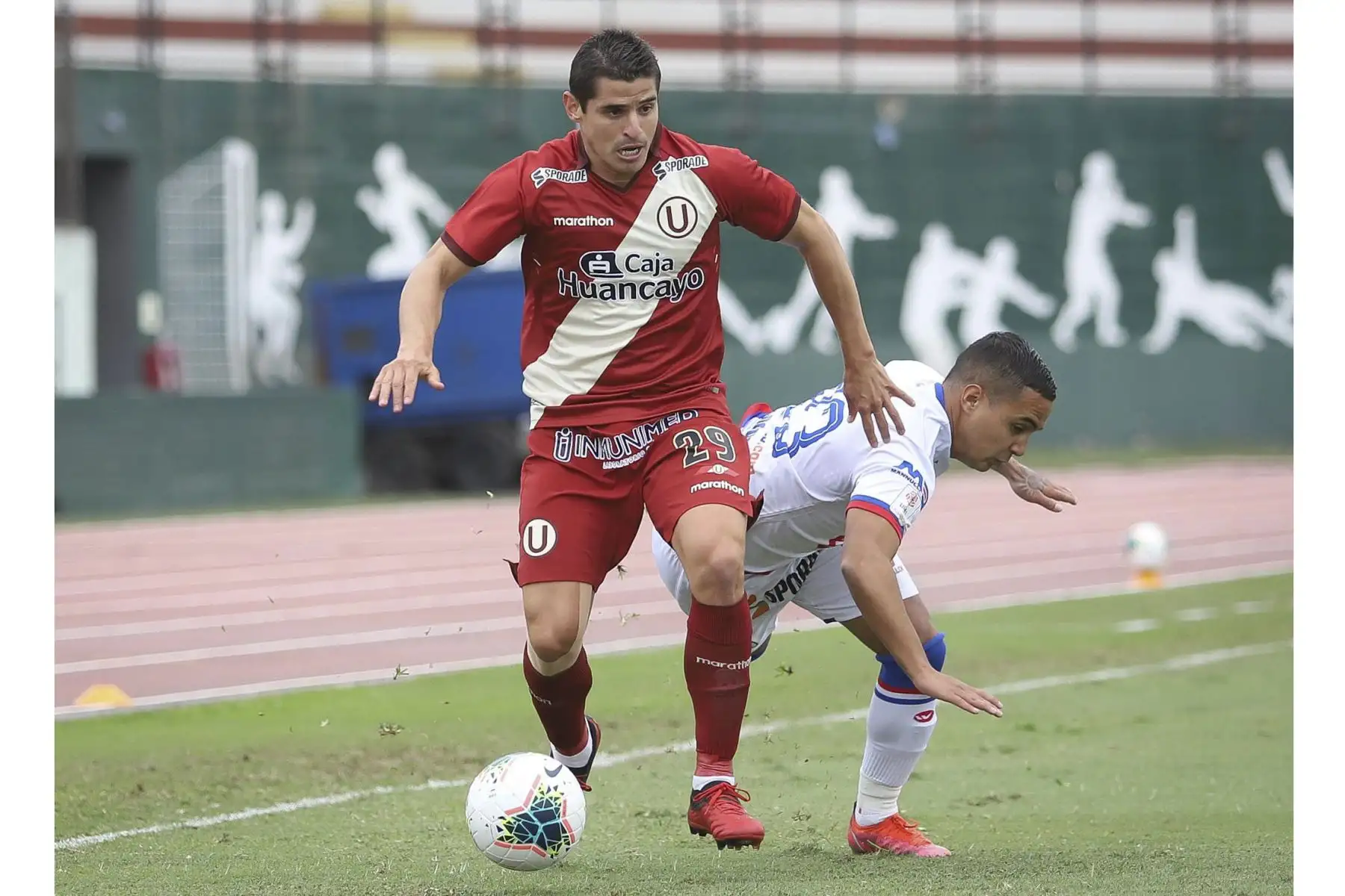 Aldo Corzo de Universitario disputa el balón ante la marca de su rival de Carlos Manucci durante partido por la tercera fecha de la Liga 1, en el Estadio Miguel Grau. Foto: Liga 1