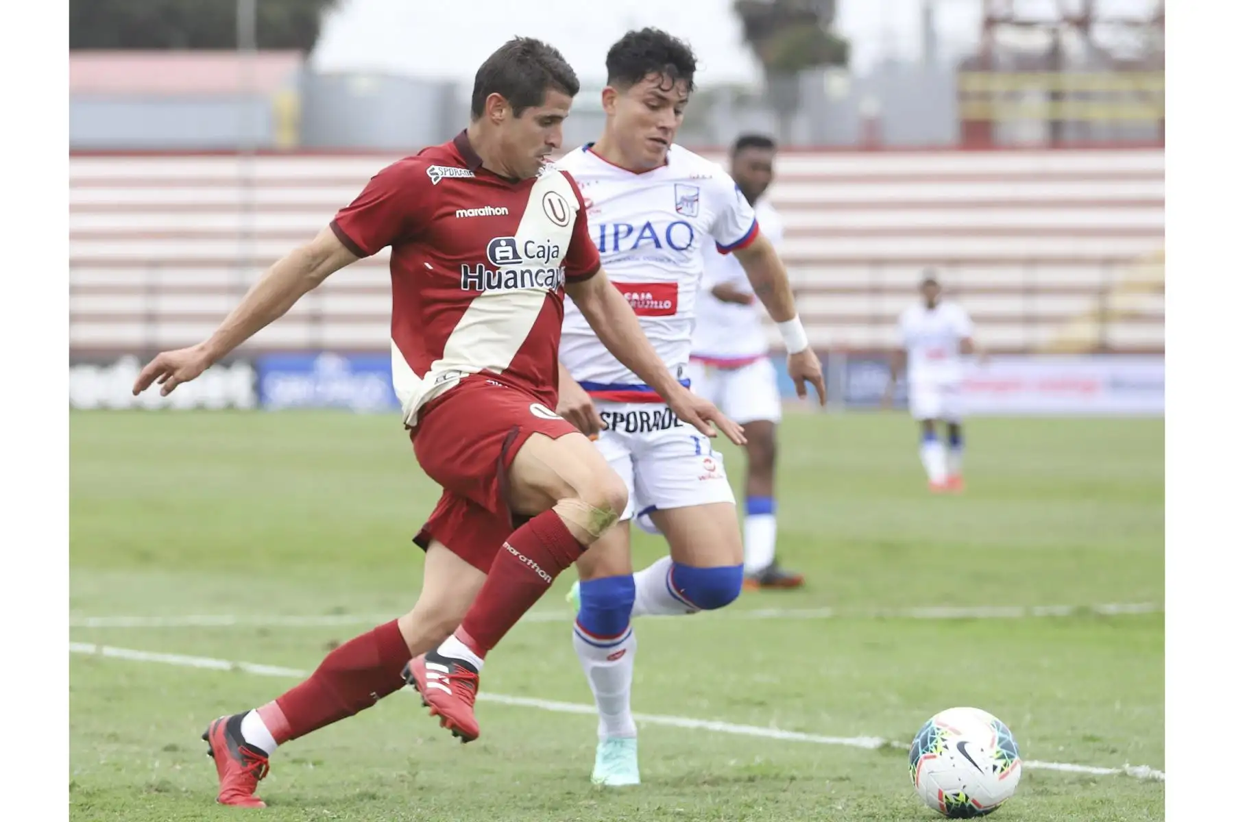 Aldo Corzo de Universitario disputa el balón ante la marca de su rival de Carlos Manucci durante partido por la tercera fecha de la Liga 1, en el Estadio Miguel Grau. Foto: Liga 1