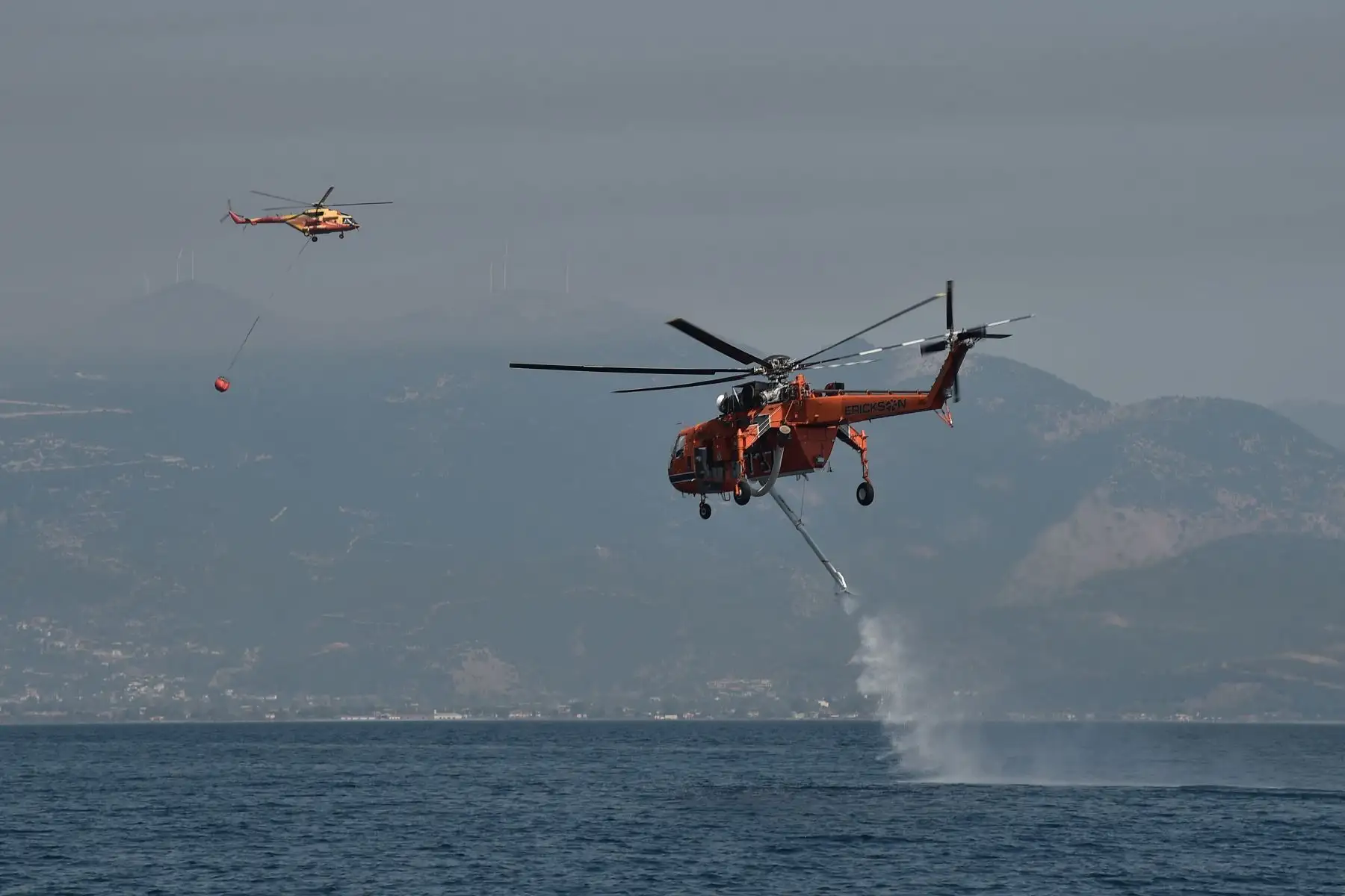 Un helicóptero Sikorsky S-64 Skycrane se llena de agua mientras lucha contra incendios cerca de la playa Lambiri en Patras en Grecia.
Foto: AFP