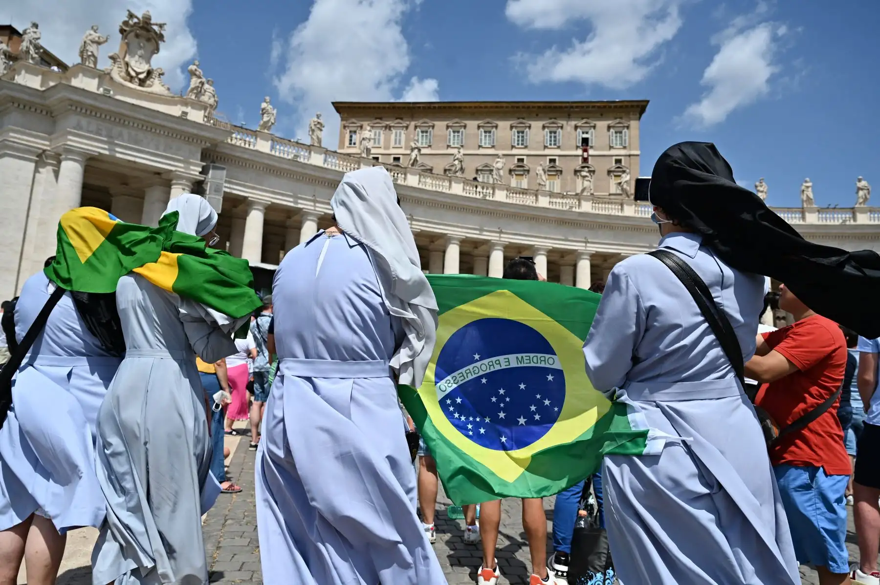 Las monjas sostienen una bandera brasileña mientras el Papa Francisco pronuncia la oración del Ángelus dominical desde la ventana de su estudio con vista a la Plaza de San Pedro en el Vaticano.
Foto: AFP