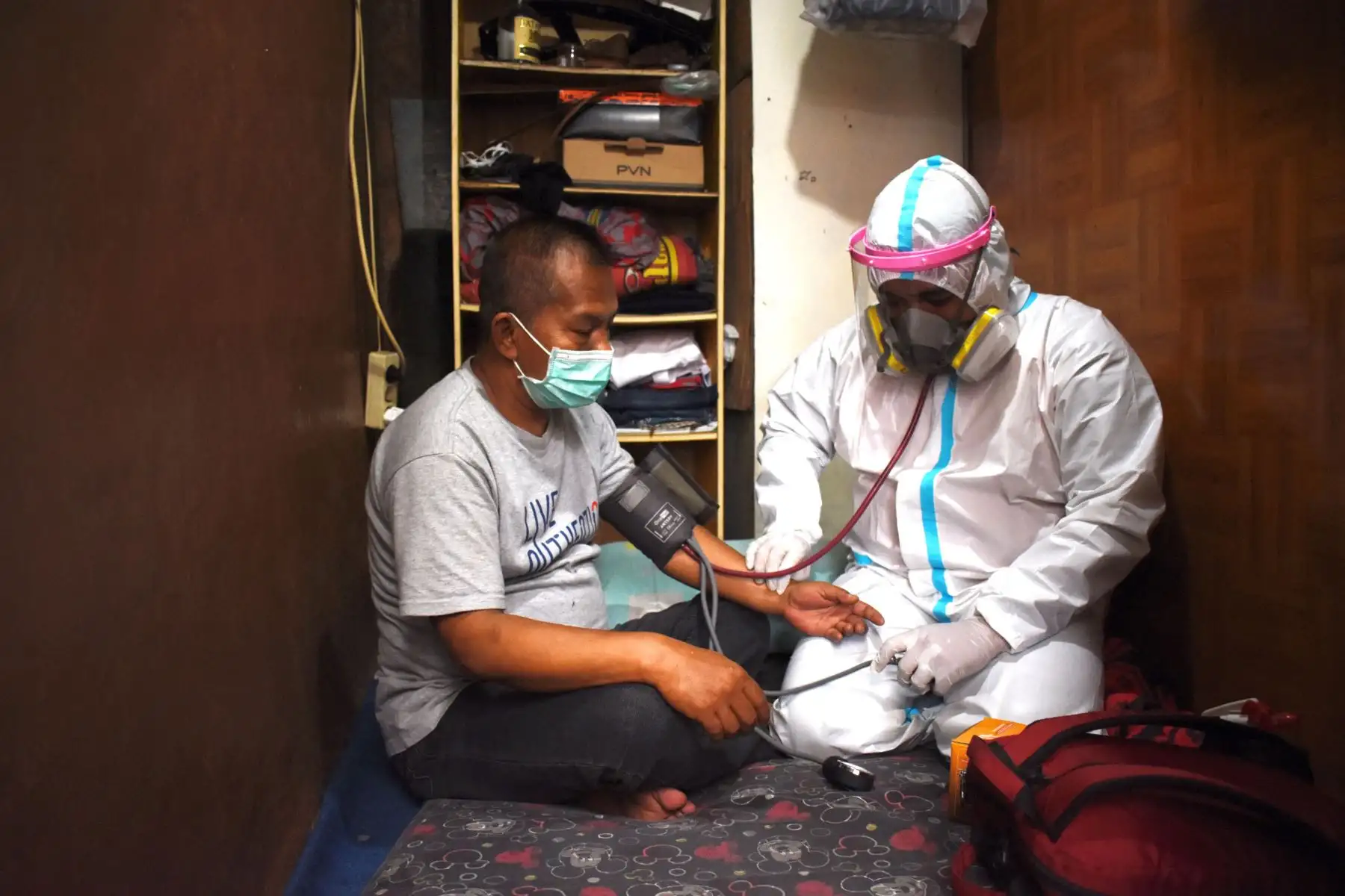 Un trabajador de salud controla a un residente que se aísla por sí mismo durante la pandérmica del coronavirus en su casa en Bandung.
Foto: AFP