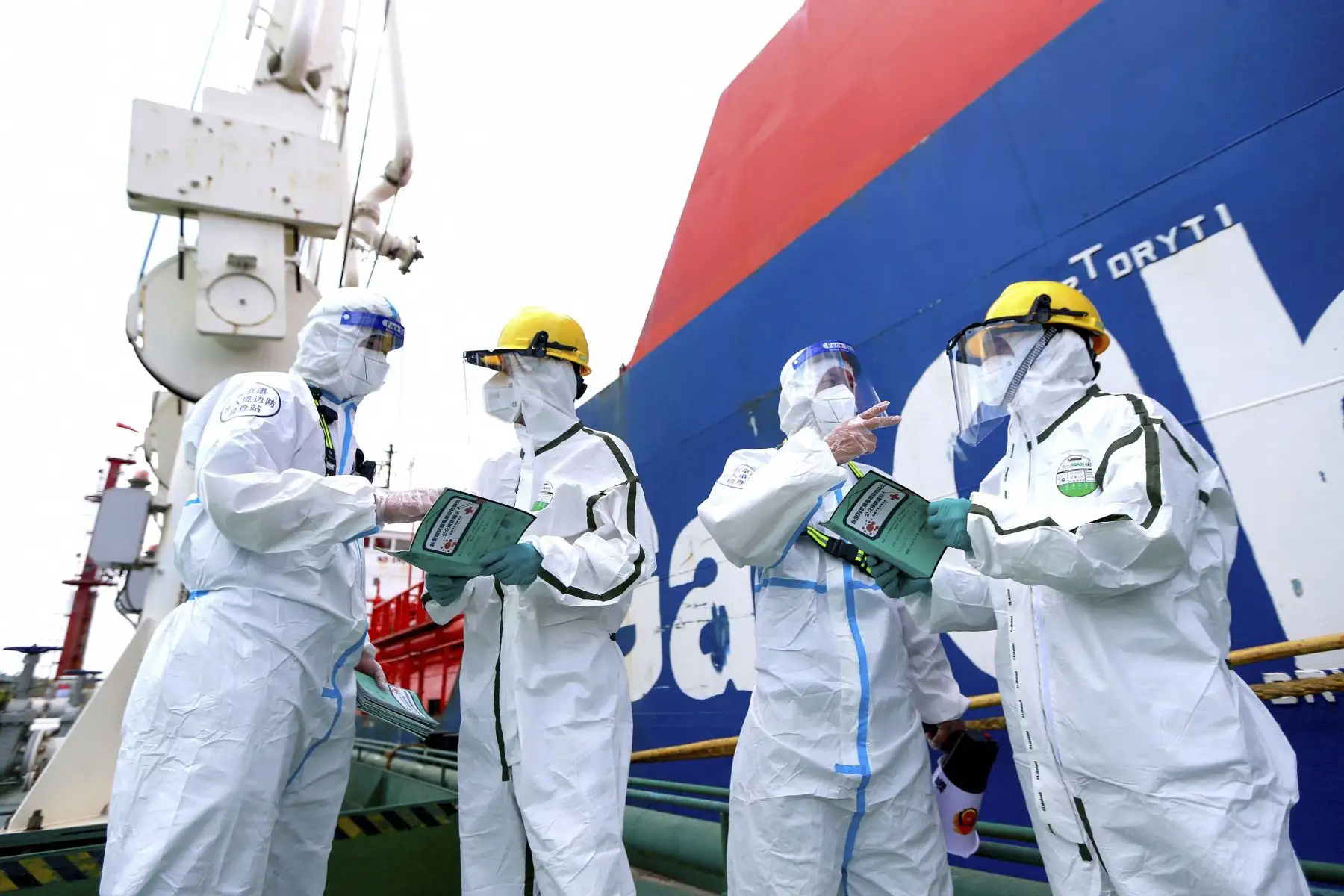 Los agentes de policía con equipo de protección explican la información de prevención de la pandemia para luchar contra la propagación del covid-19 a los trabajadores en el puerto de Nanjing, en la provincia de Jiangsu, en el este de China.
Foto: AFP