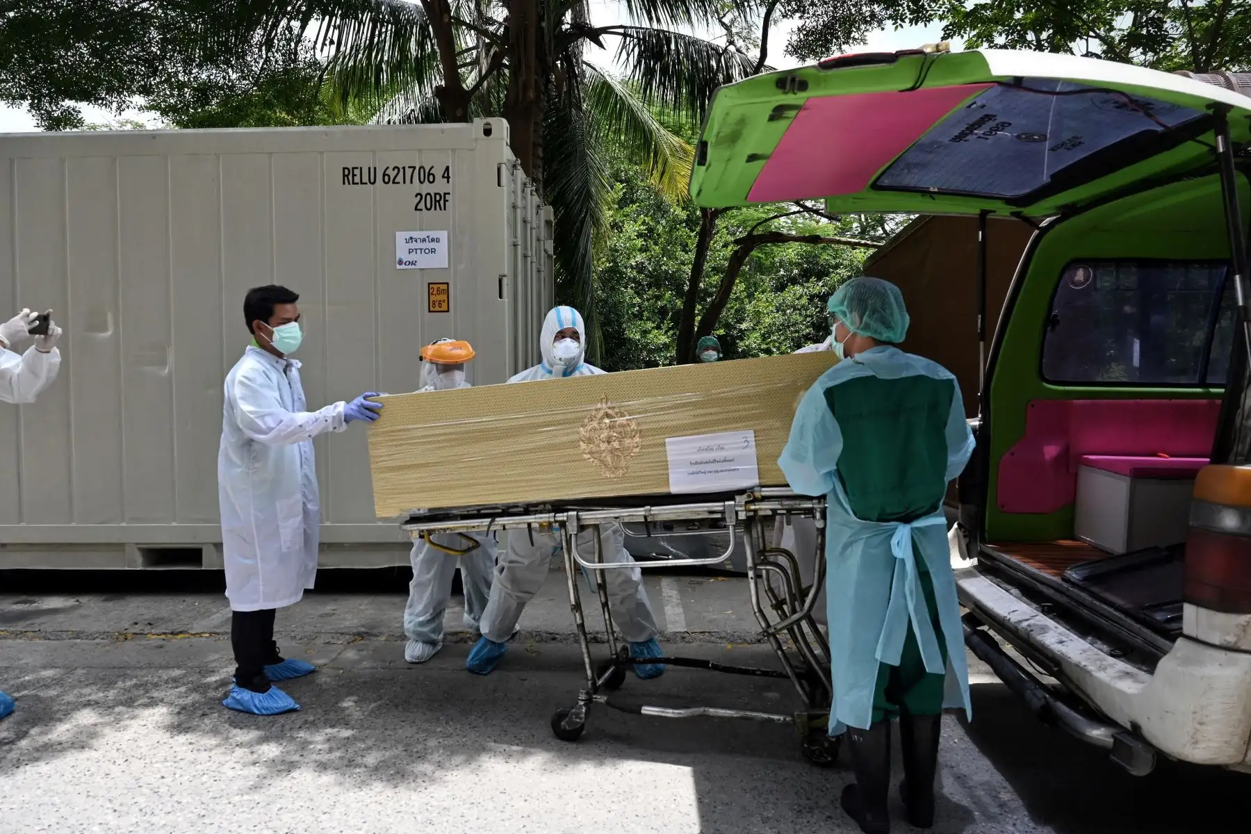 Los trabajadores del hospital trasladan a las víctimas del coronavirus de un contenedor de almacenamiento refrigerado a ataúdes fuera de la morgue del Hospital Thammasat en la provincia de Pathum Thani, al norte de Bangkok.
Foto: AFP