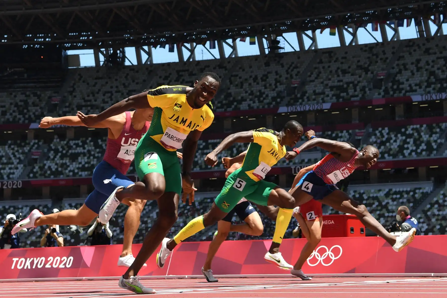 Hansle Parchment de Jamaica cruza la línea de meta para ganar por delante del segundo clasificado de Estados Unidos Grant Holloway  y el tercer clasificado de Jamaica Ronald Levy en la final masculina de 110 metros con vallas, durante los Juegos Olímpicos de Tokio 2020 en el estadio Olímpico de Tokio. FOTO:AFP