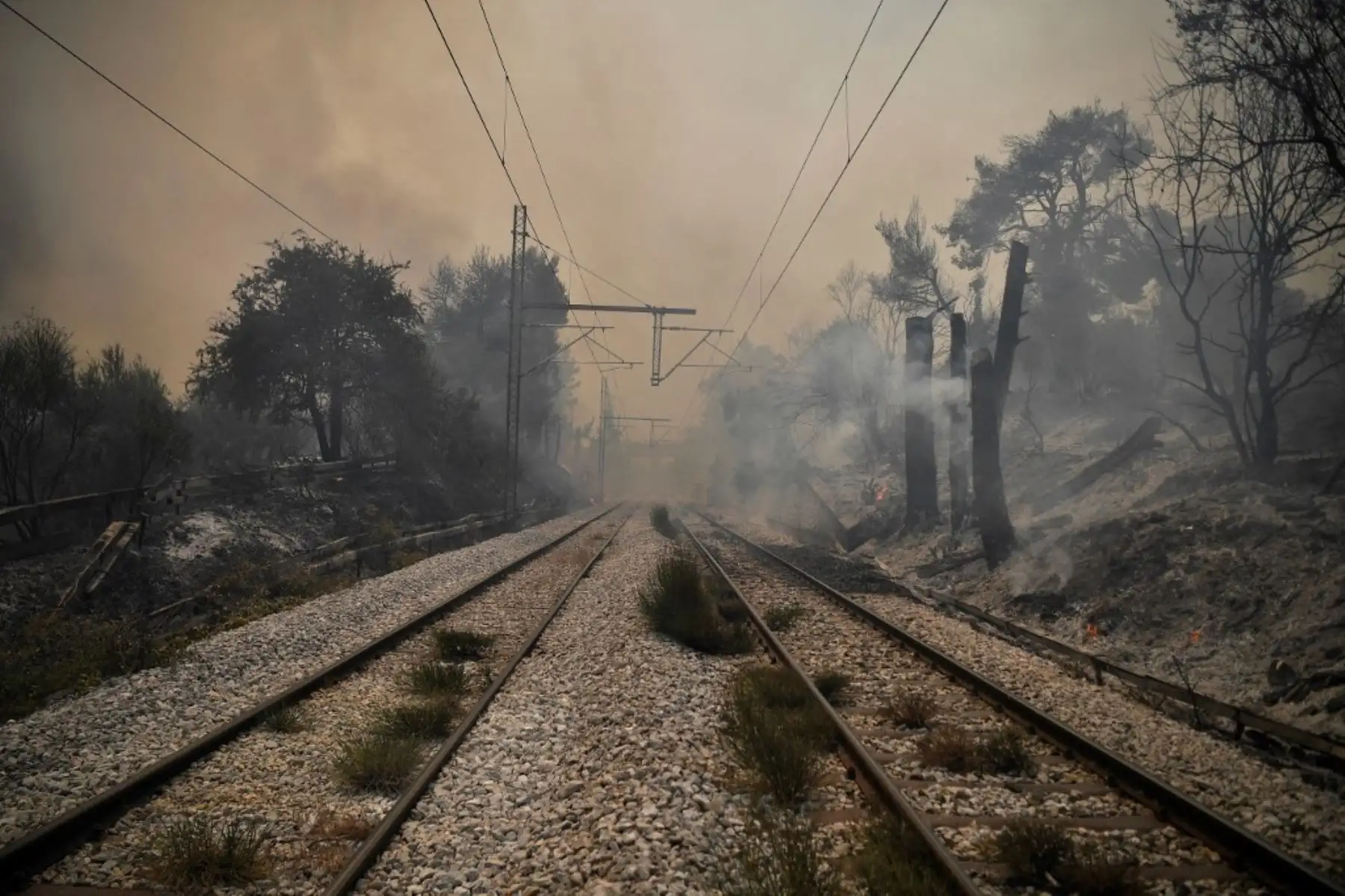 Una fotografía tomada el 6 de agosto de 2021 muestra un ferrocarril en el humo mientras un incendio se propaga en el pueblo de Afidnes, a unos 30 kilómetros al norte de Atenas. - Cientos de bomberos lucharon contra un incendio en las afueras de Atenas el 6 de agosto mientras decenas de incendios se desataban en Grecia. Foto: AFP