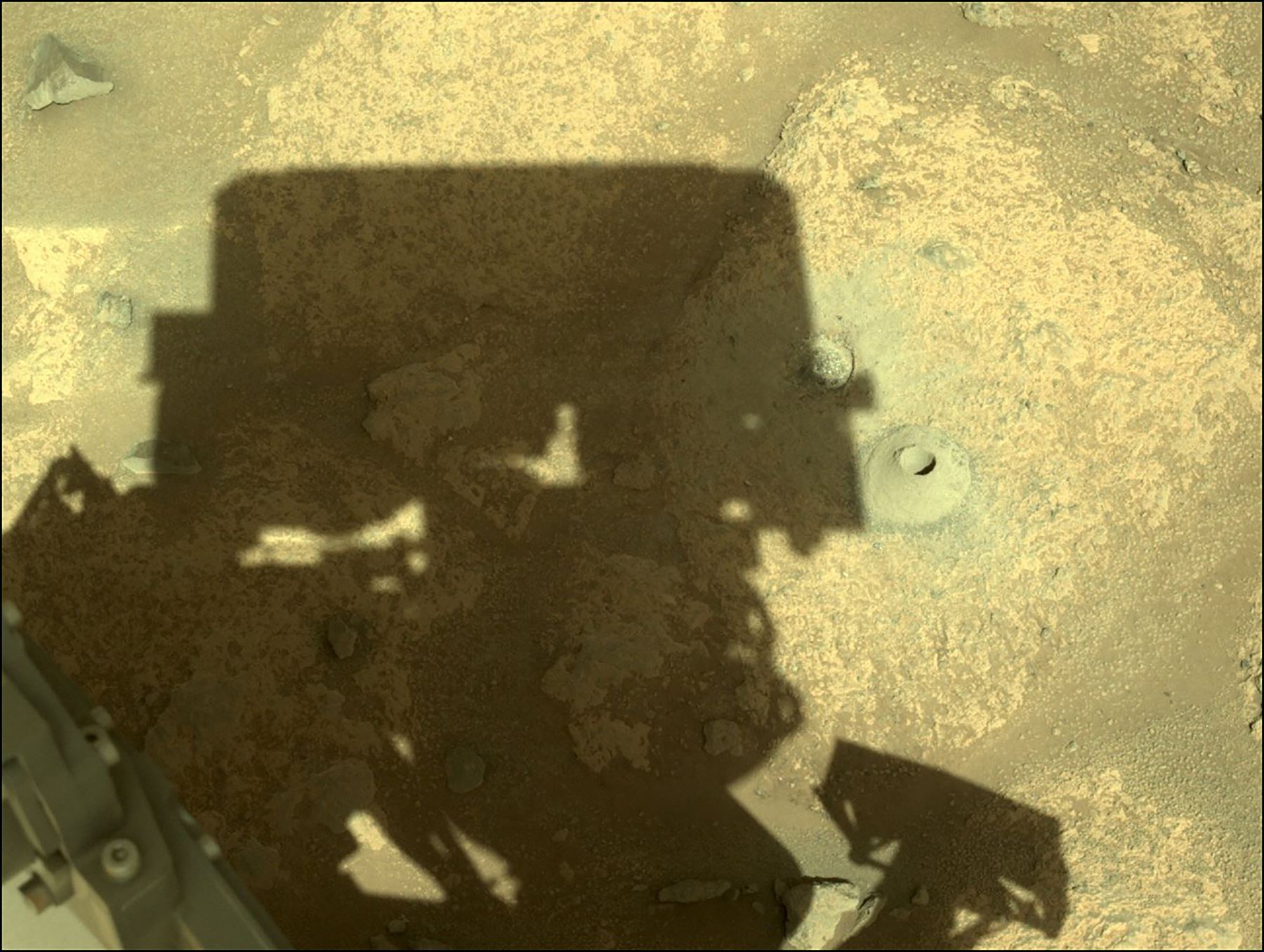 La sombra del rover Perseverance Mars se proyecta junto a su primer agujero perforado en una roca. Foto: AFP