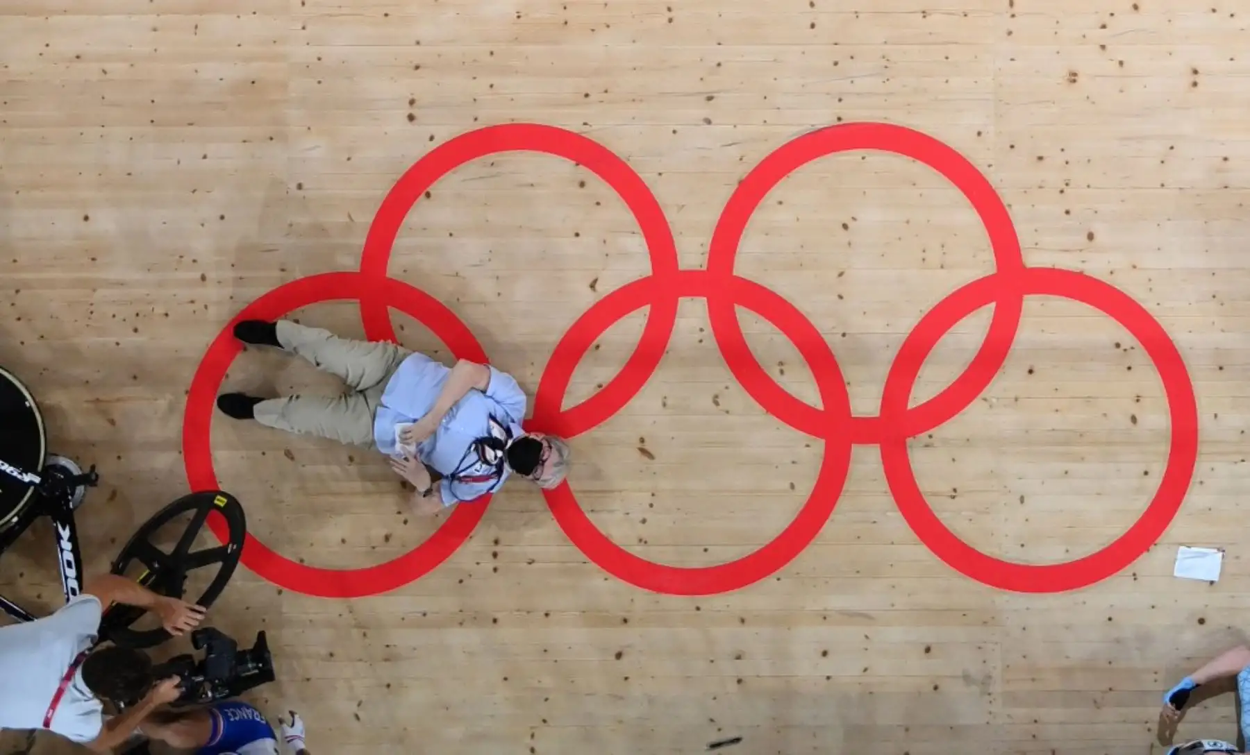 Oficial tirado en la pista después de ser atropellado por ciclistas que se estrellaron durante la carrera de scratch omnium. Foto: AFP