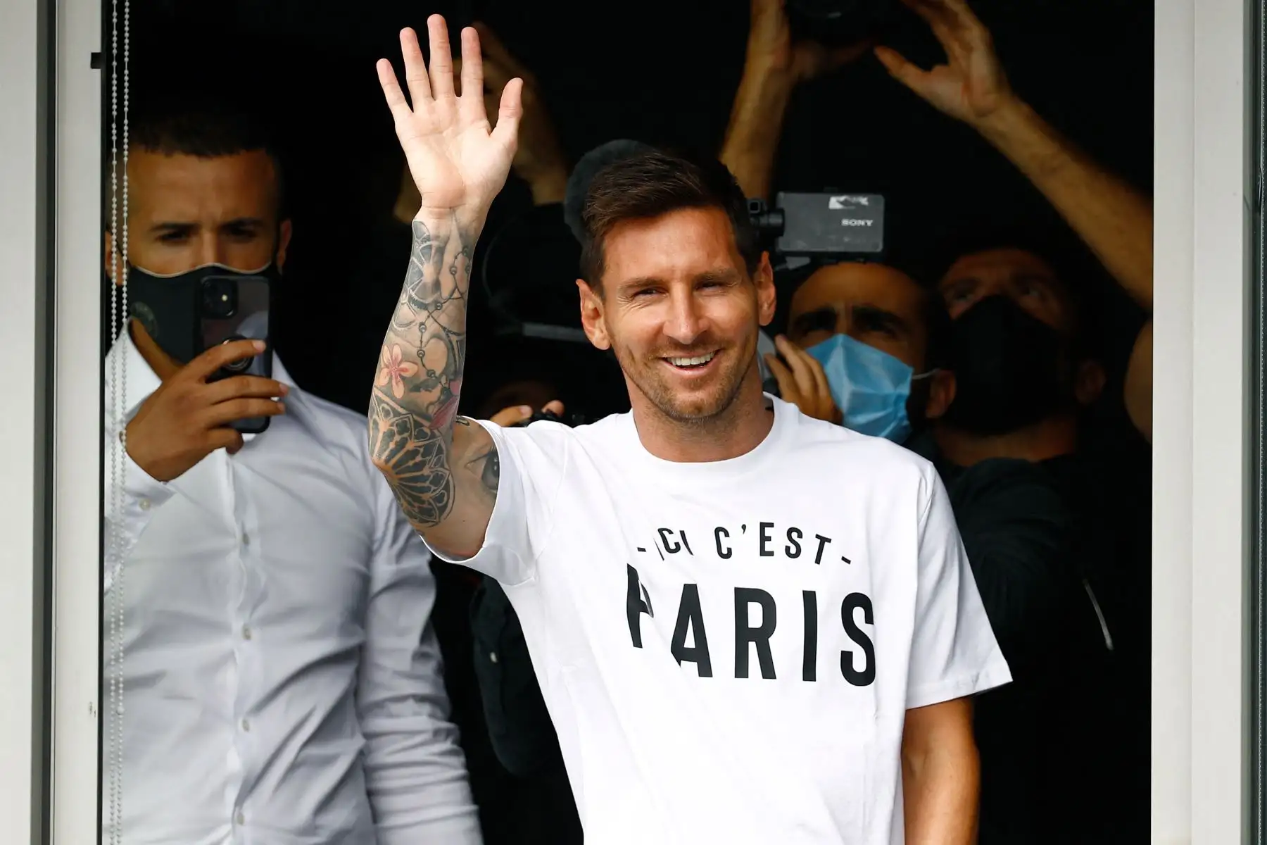El futbolista argentino Lionel Messi saluda a los aficionados desde una ventana después de aterrizar el 10 de agosto de 2021 en el aeropuerto de Le Bourget, al norte de París. Foto: AFP
