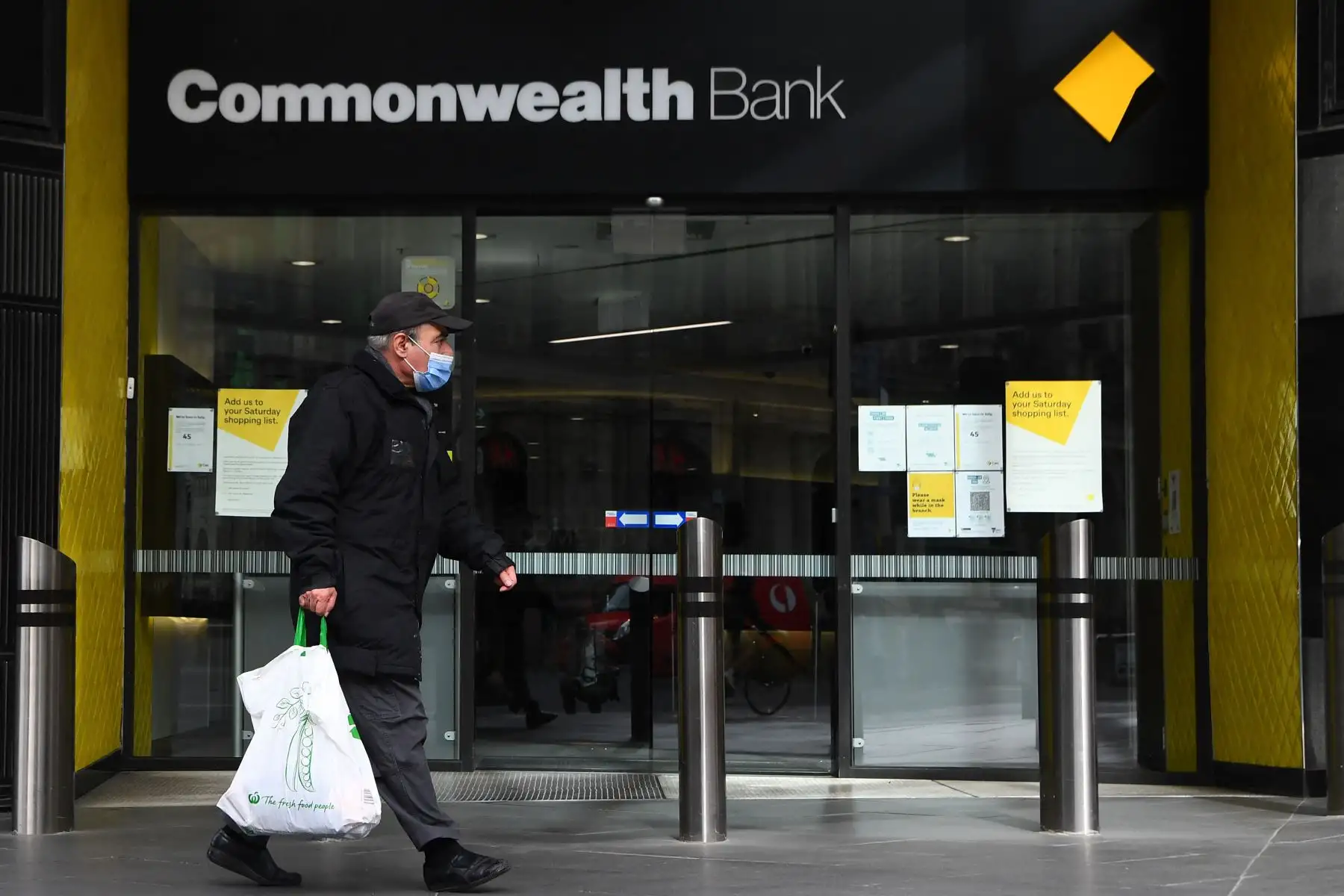 La gente pasa frente a una sucursal de la  Commonwealth Bank of Australia  en Melbourne, cuando las autoridades dan la orden de confinamiento en la ciudad. 
Foto: AFP