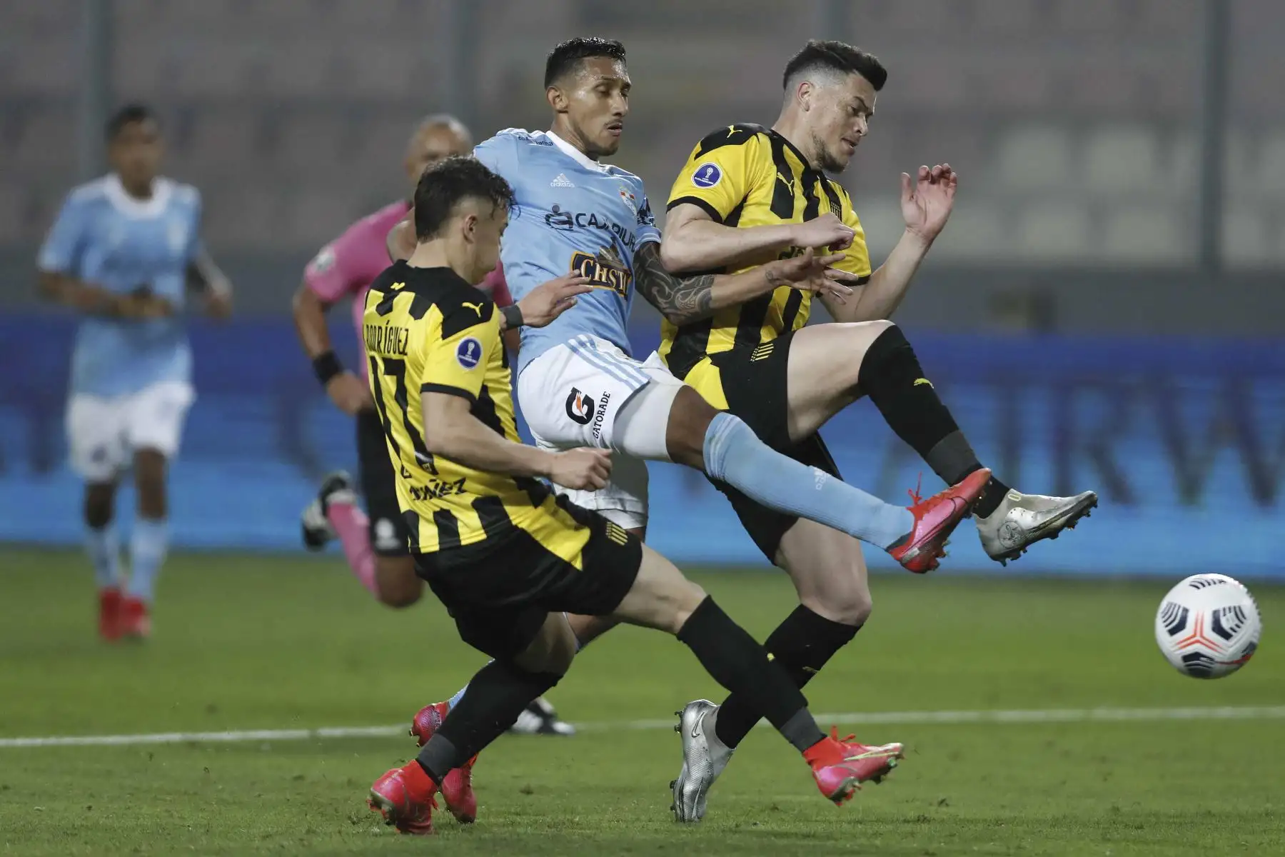 Christofer Gonzales de Sporting Cristal compite por el balón con los uruguayos de Peñarol Diego Rodríguez y Carlos Rodríguez durante partido por los cuartos de final de la Copa Sudamericana, en el Estadio Nacional. Foto: AFP