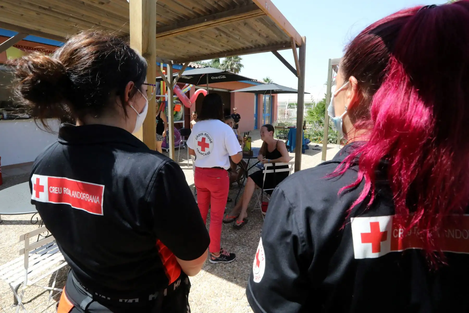 Miembros de la Cruz Roja Francesa caminan por un callejón para encontrarse con los vacacionistas durante una campaña de concienciación sobre la vacunación contra el covid-19 en un campamento  en Argeles, en el sur de Francia. 
Foto: AFP