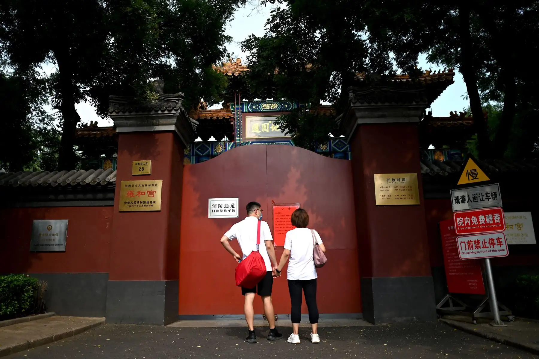 La gente mira un aviso publicado fuera del Templo Lama, cerrado al público como parte de las medidas para contener el peor brote de covid-19 del país en meses, en Beijing.
Foto: AFP