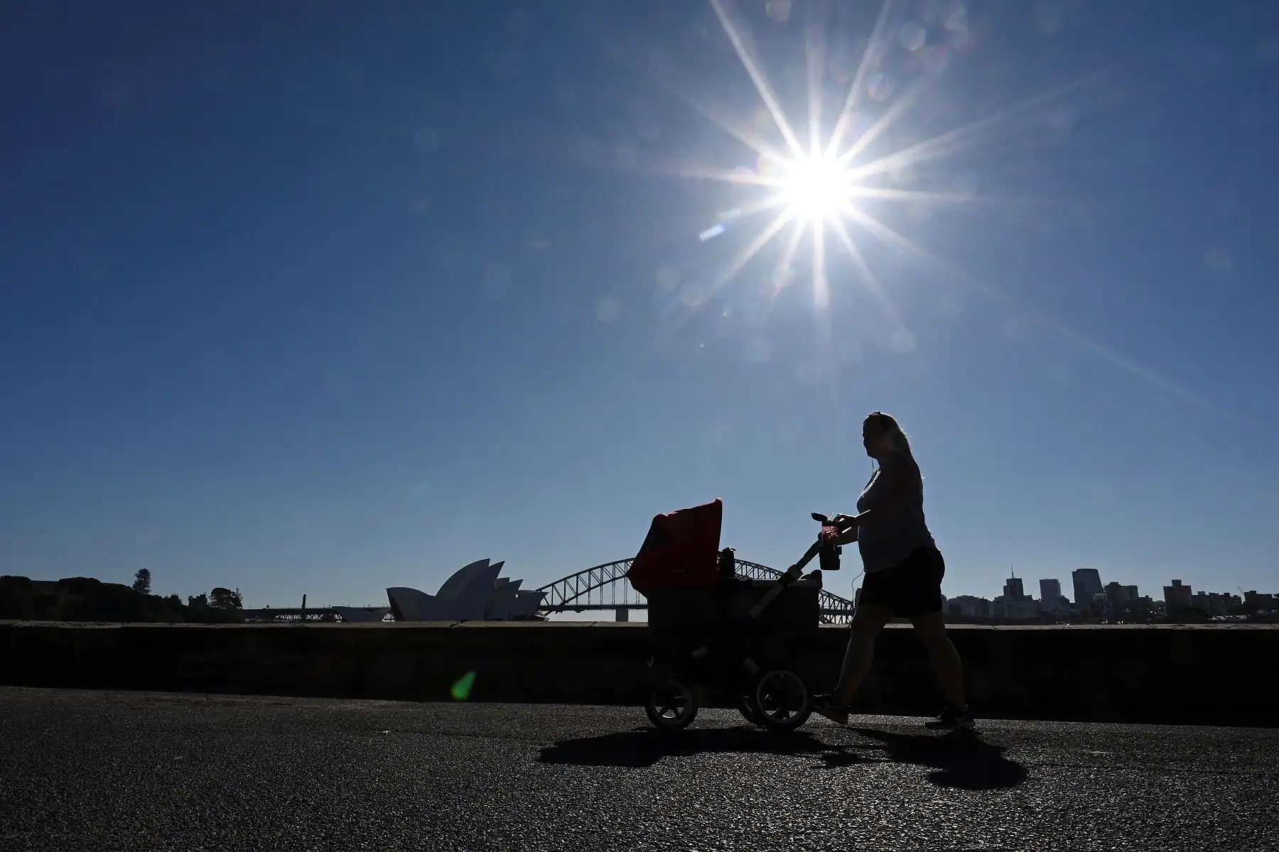 Una mujer empuja un cochecito de bebé a lo largo del paseo marítimo del puerto de Sydney con la Ópera en la distancia en medio de un bloqueo prolongado debido a la pandemia de covid-19.
Foto: AFP