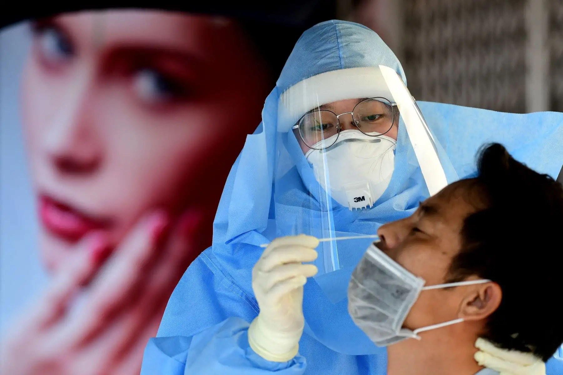 Un trabajador de la salud que usa equipo de protección personal recolecta muestras de hisopos de un hombre  para la prueba del coronavirus covid-19 en Hanoi.
Foto: AFP