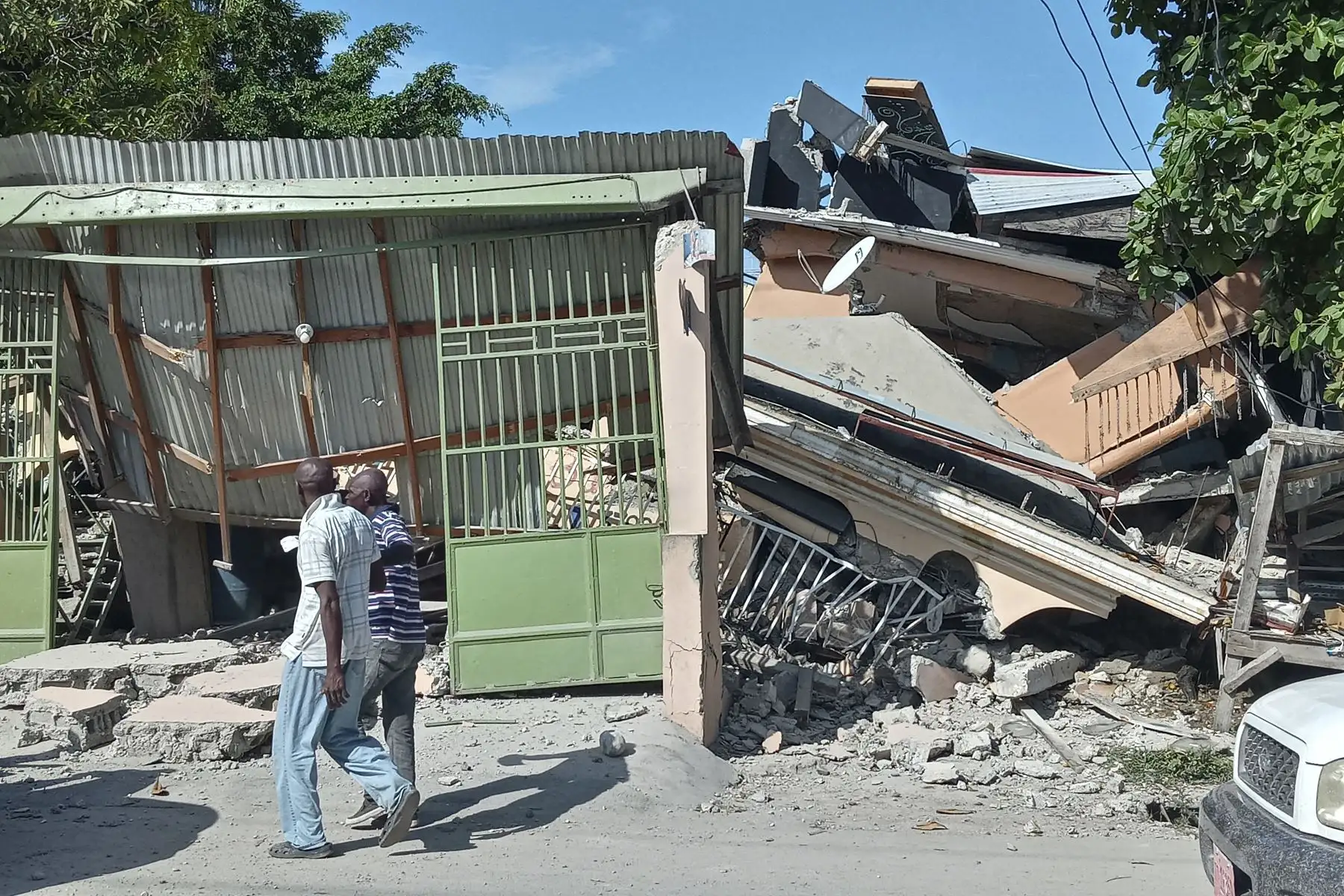 2021. Las peronas caminam junto a una casa derrumbada por el terremoto de magnitud 7,2 grados, en Los Cayos, Haití. Foto: AFP