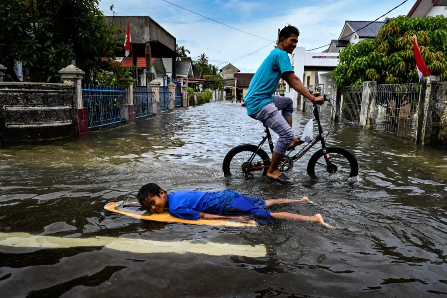 Un niño usa una tabla de surf en las aguas de la inundación después de las fuertes lluvias en una zona residencial de Ajun en las afueras de Banda Aceh, Indonesia el 11 de agosto de 2021.